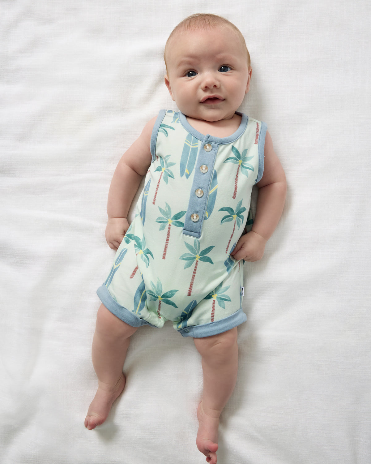 Overhead view of newborn wearing the Palm Dunes Tank Button Romper