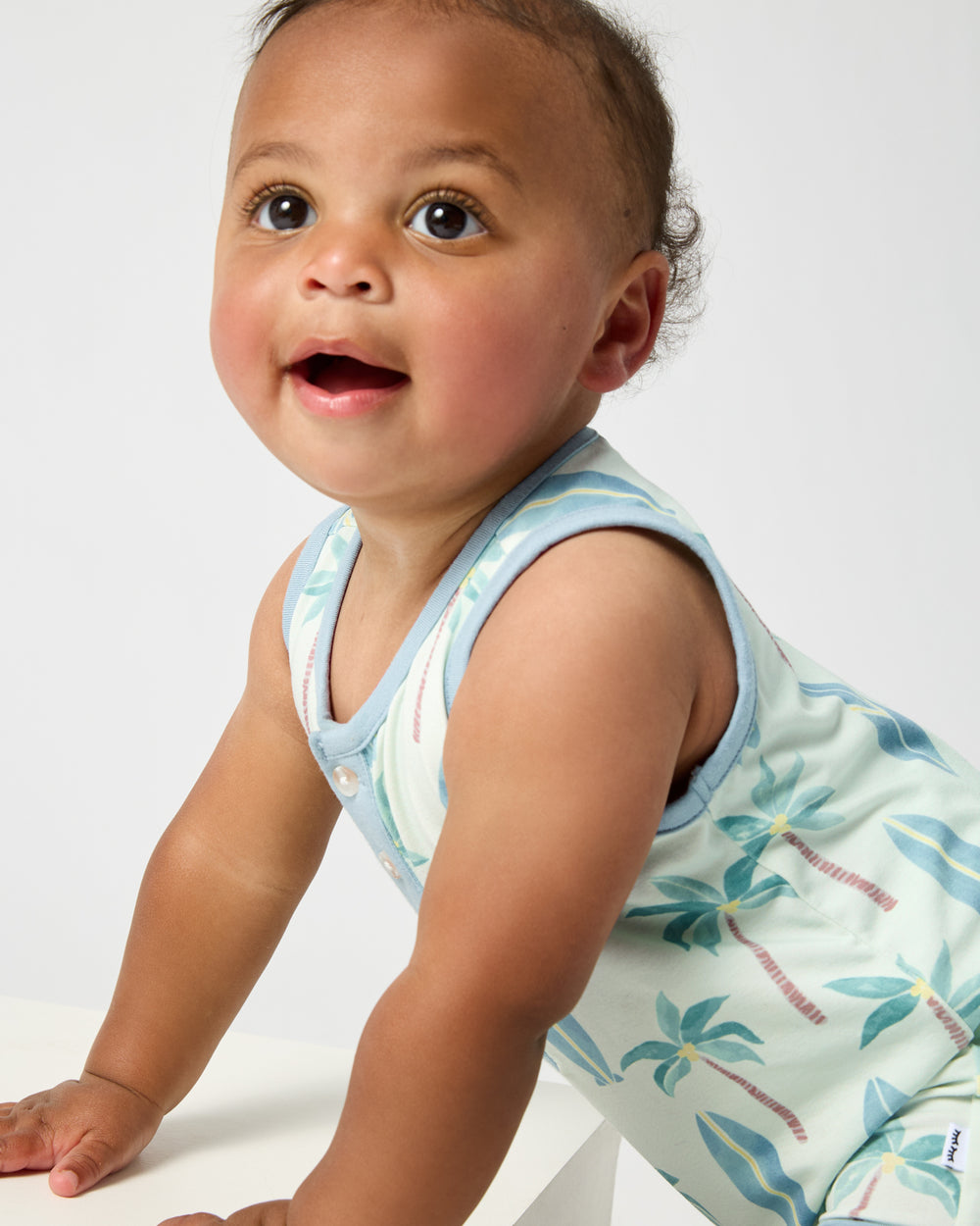 Close up of baby wearing the Palm Dunes Tank Button Romper