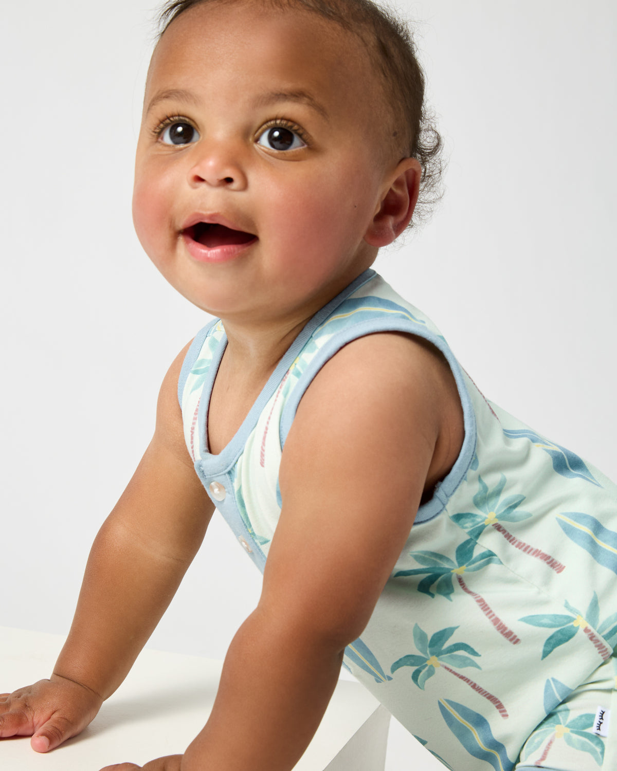 Close up of baby wearing the Palm Dunes Tank Button Romper
