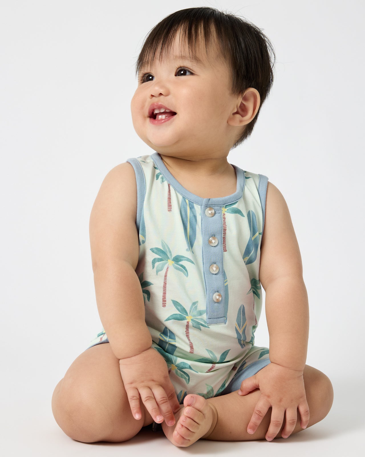 Sitting baby wearing the Palm Dunes Tank Button Romper