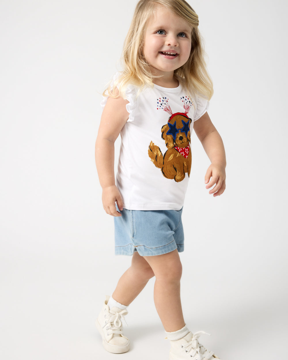 Girl wearing the Star Spangled Pup Flutter Tee with denim shorts