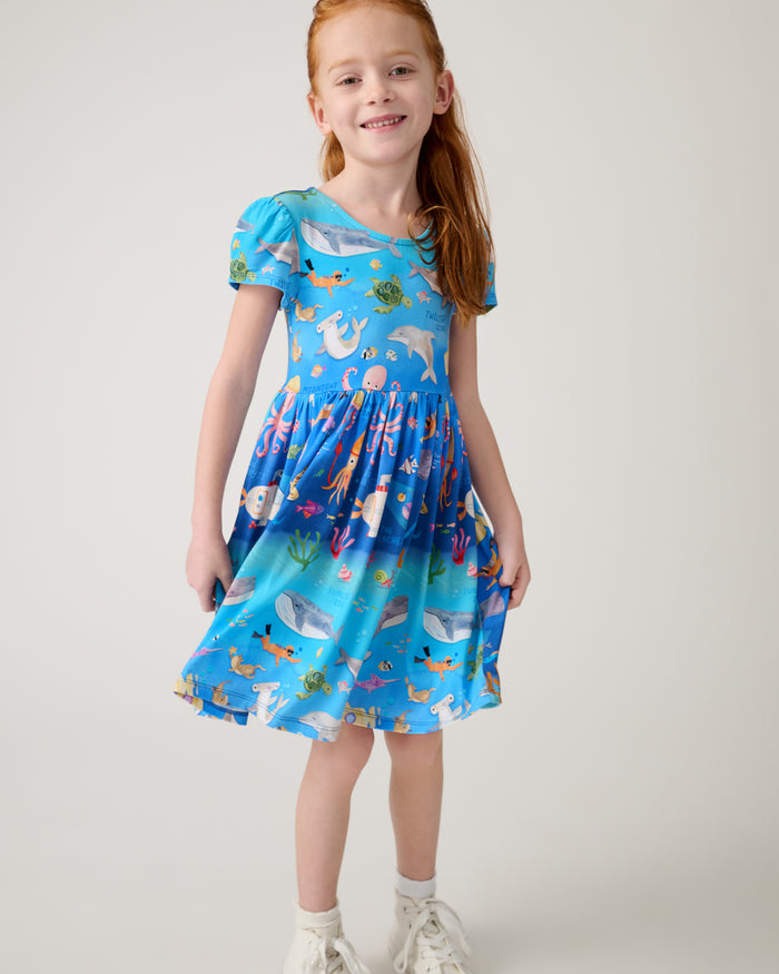 Girl wearing the Underwater Discovery Bow Back Skater Dress