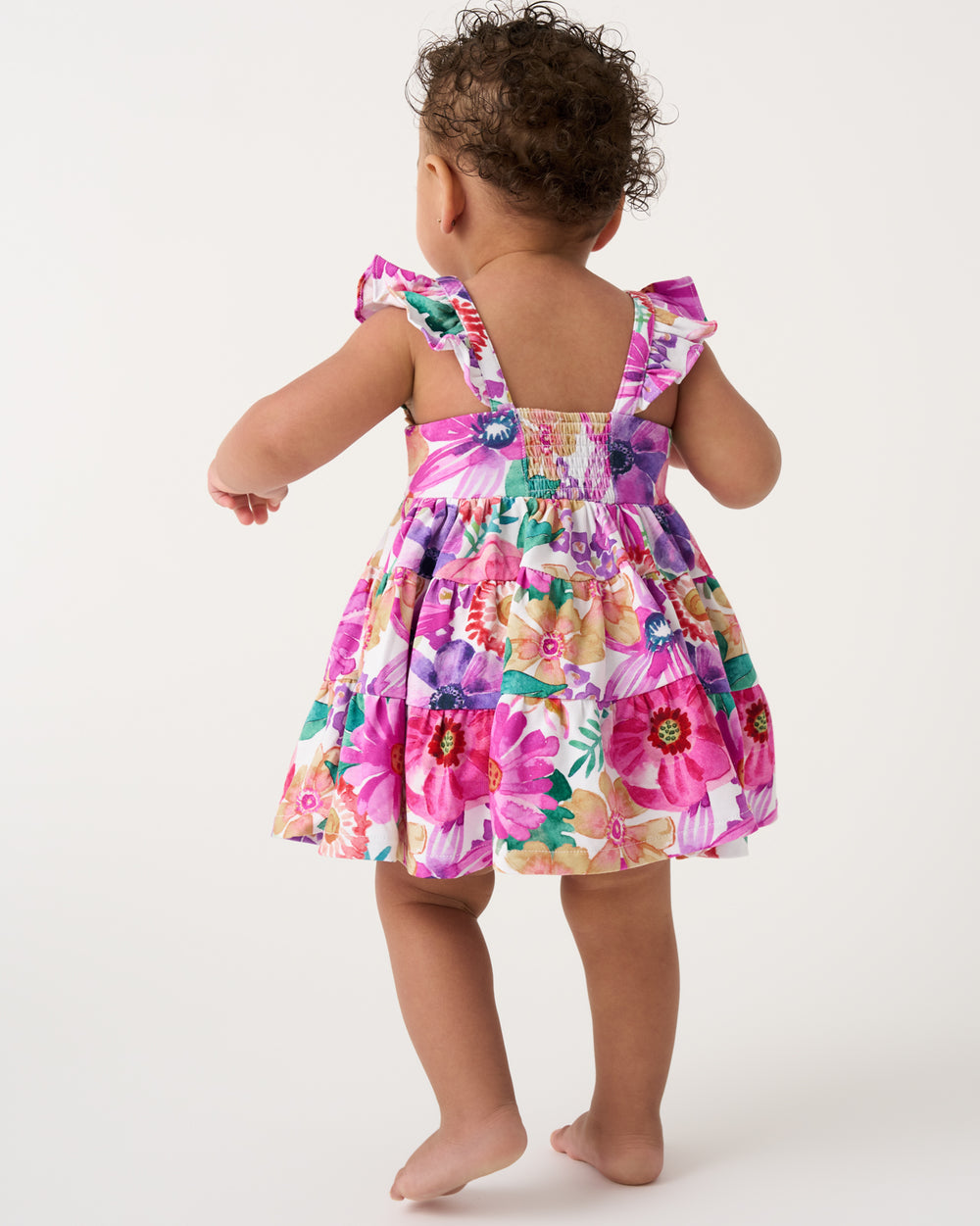 Back view of baby wearing the Hibiscus Blooms Tiered Flutter Dress with Bloomer