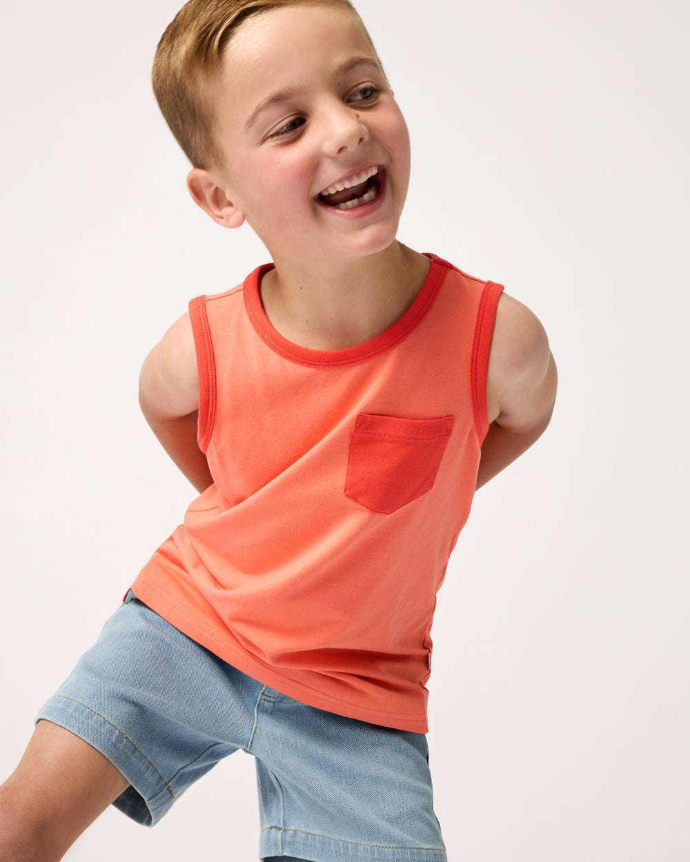 Boy wearing the Orange Crush Pocket Tank with denim chino shorts