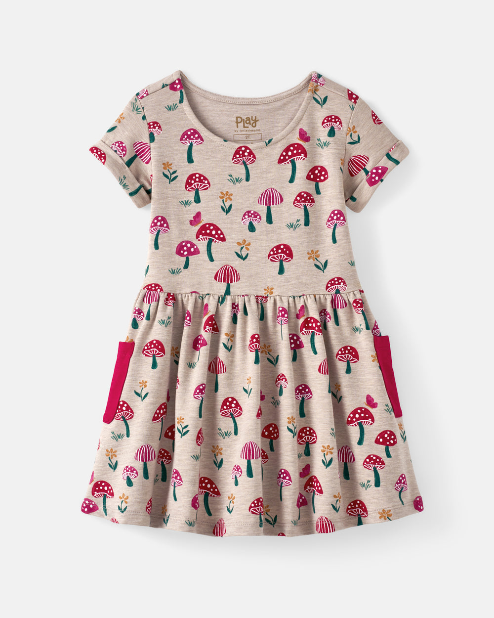 A toddler girl's short-sleeve dress with a beige heathered base, featuring an all-over print of red and pink mushrooms, green stems, and small yellow flowers. The dress has a gathered waist and two bright pink side pockets, shown against a light gray background.