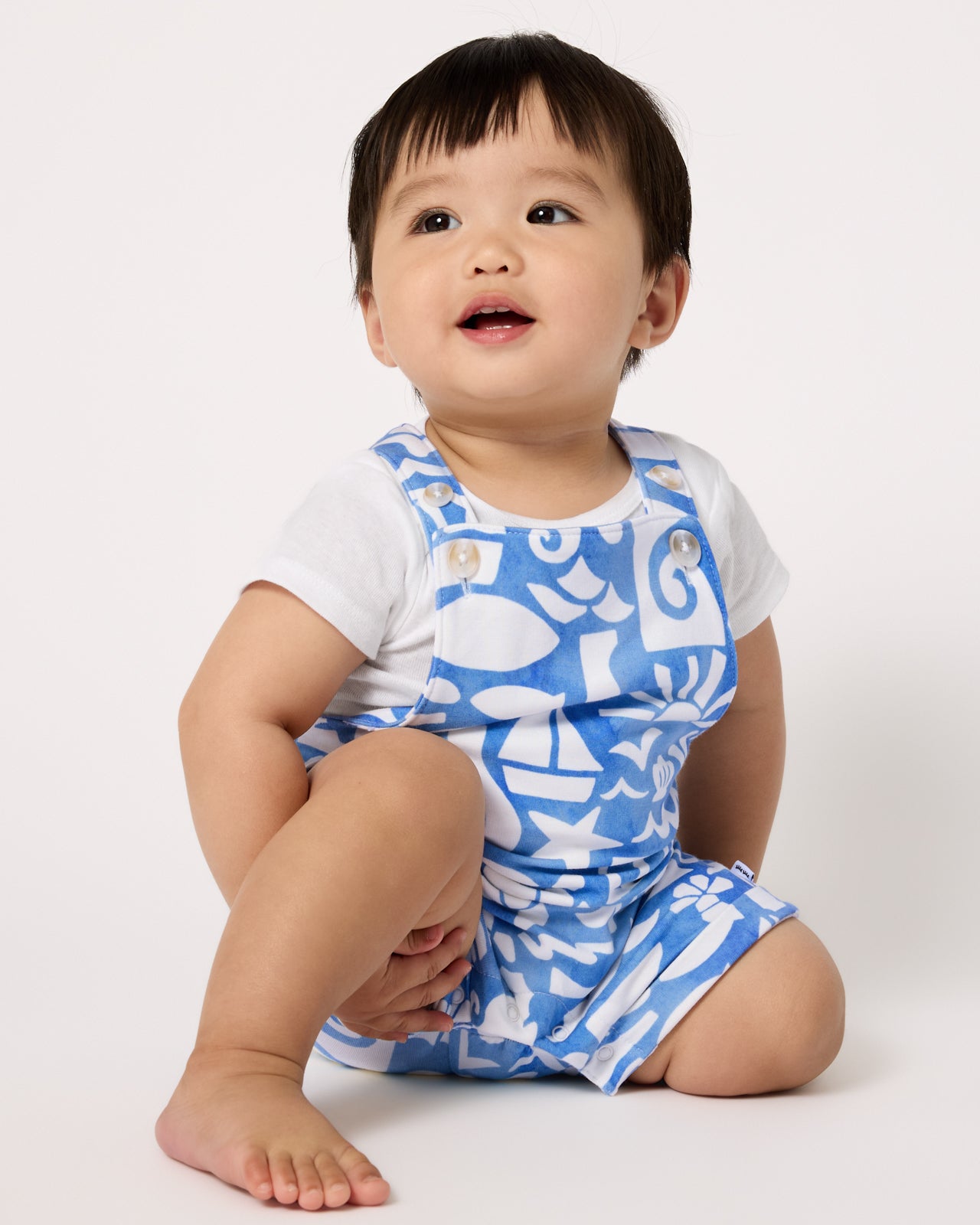 Baby wearing the Summer Shores Shorty Overall and white bodysuit