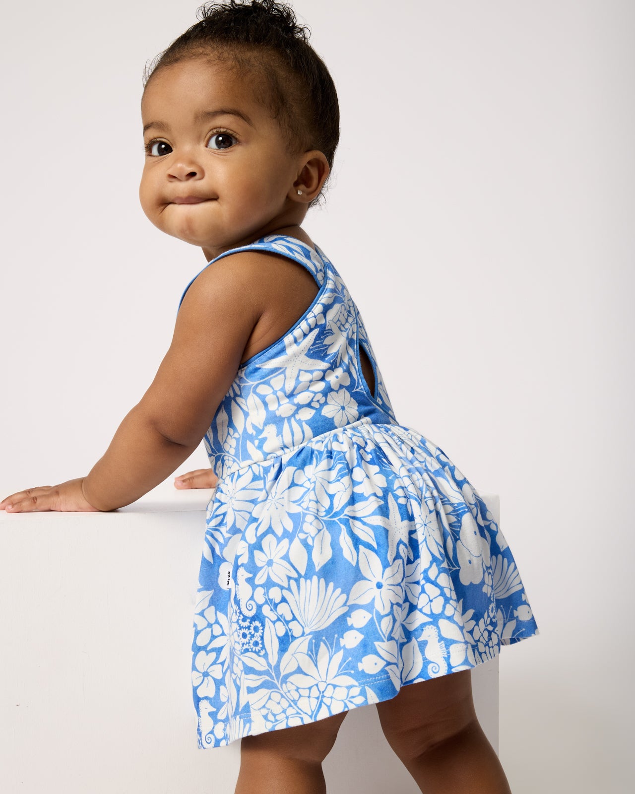Standing baby wearing the Azure Garden Cross Back Skater Dress with Bloomer