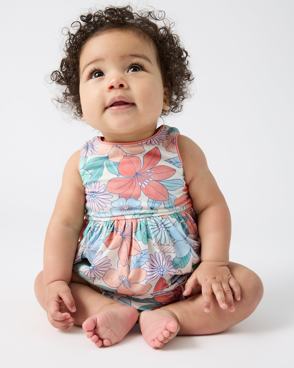 Sitting newborn wearing the Shoreline Blooms Cross Back Skater Dress with Bloomer