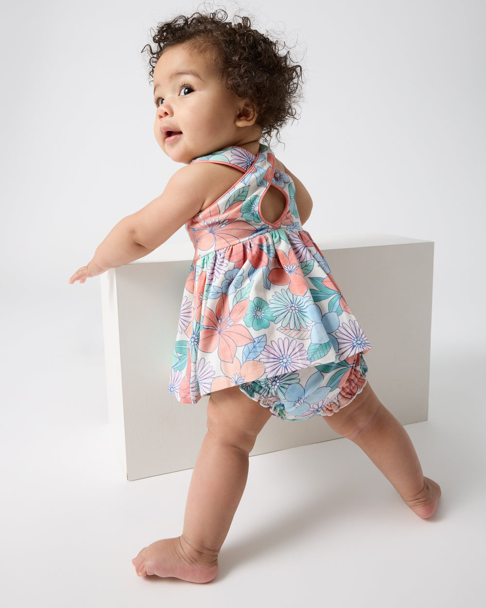 Standing baby wearing the Shoreline Blooms Cross Back Skater Dress with Bloomer
