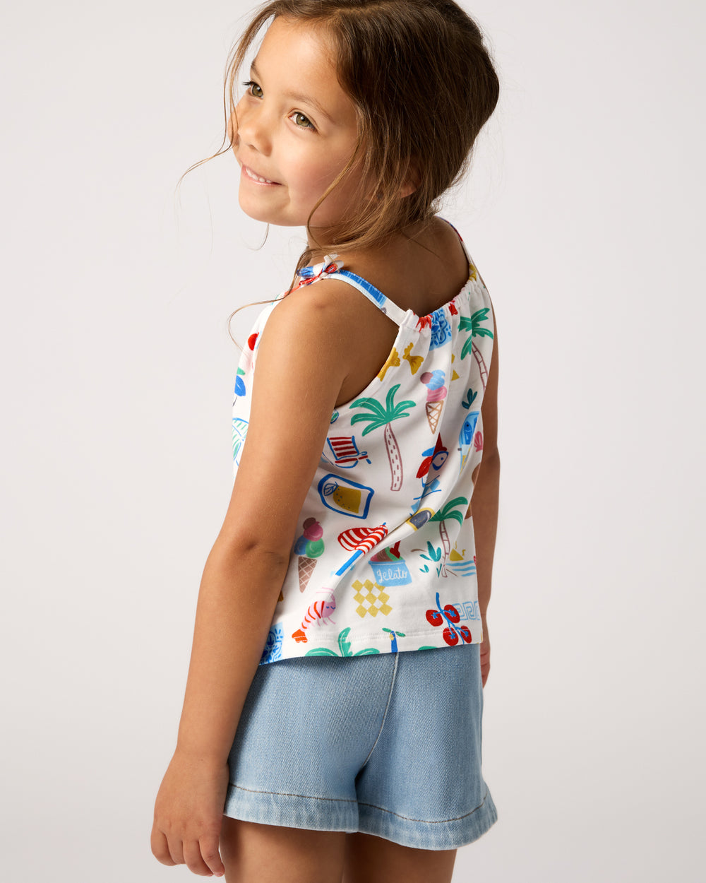 Back view of child wearing the Ciao Bella Bow Strap Tank with denim shorts