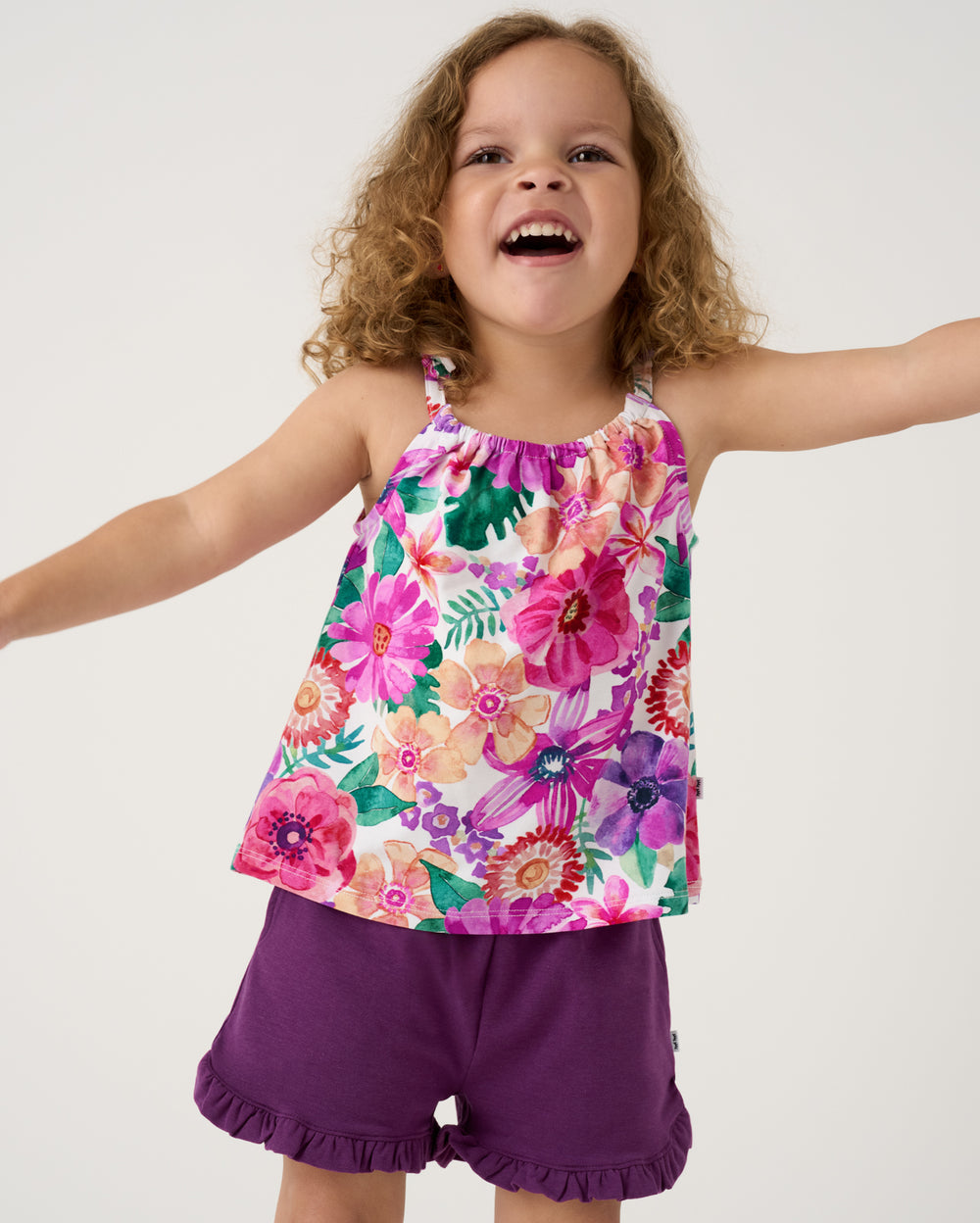 Posing girl wearing the Royal Violet Ruffle Shorts with the Hibiscus Blooms Bow Strap Tank