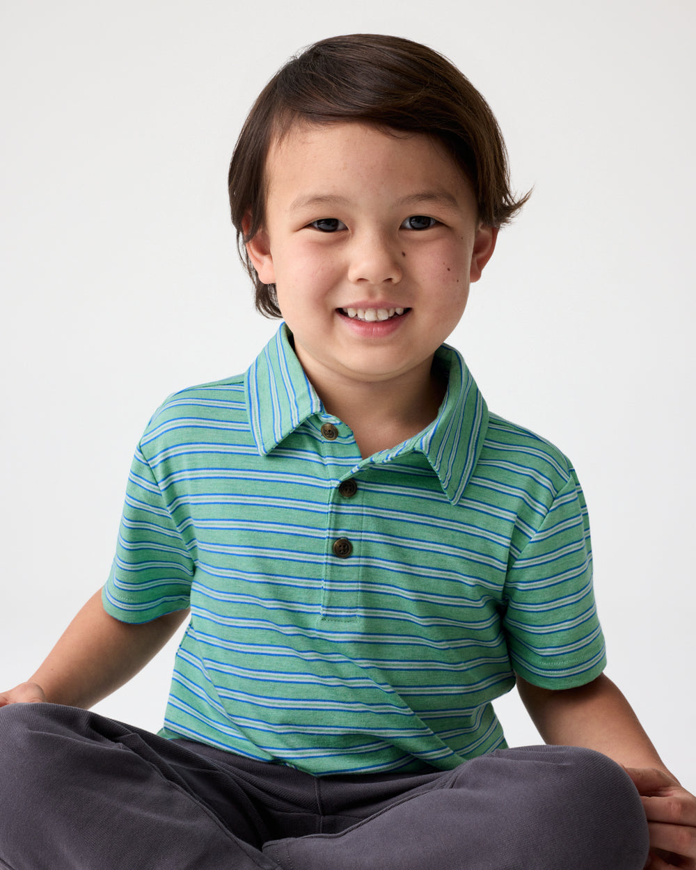 Sitting boy wearing the Fresh Green Heather Stripes Polo Shirt 