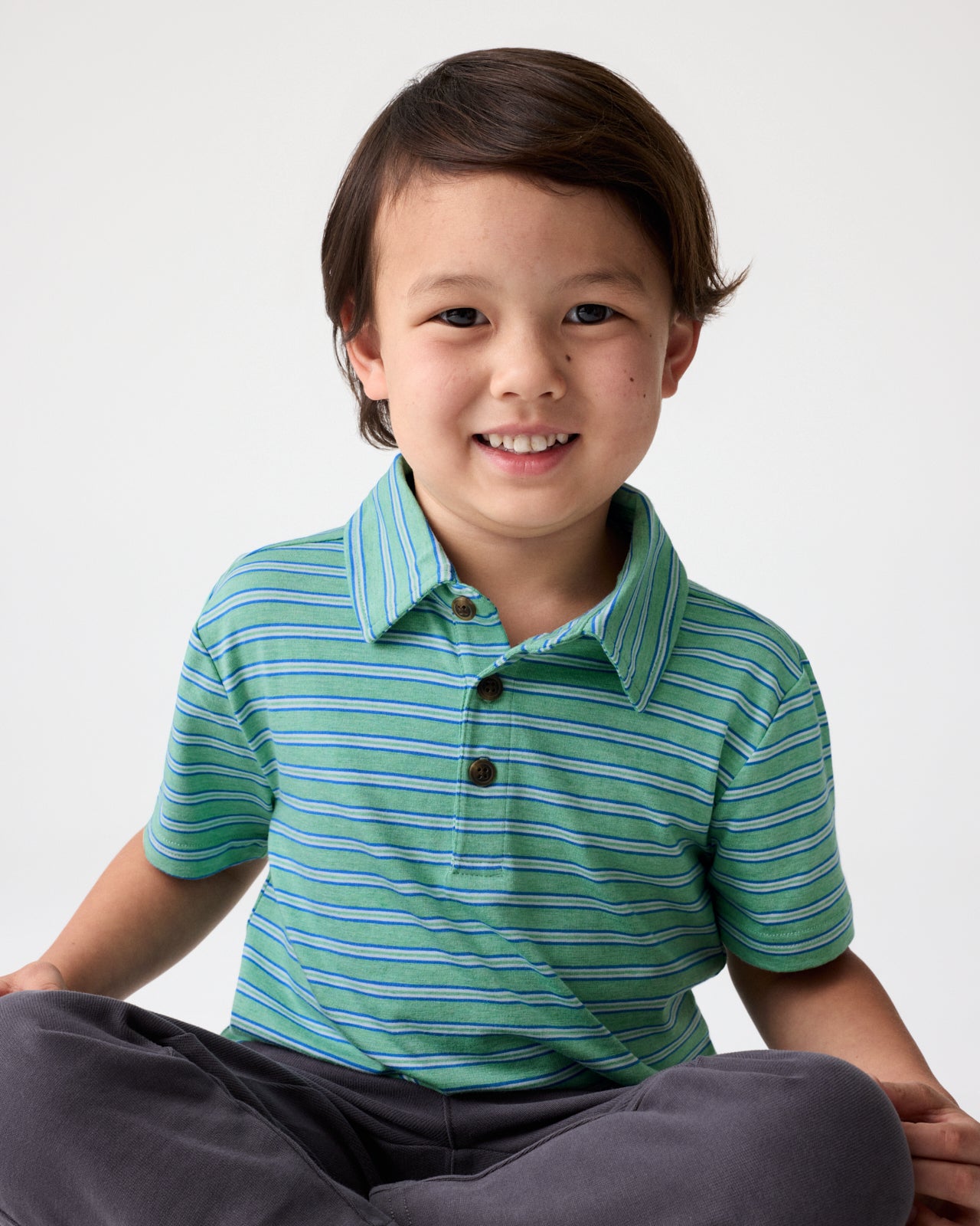 Sitting boy wearing the Fresh Green Heather Stripes Polo Shirt 