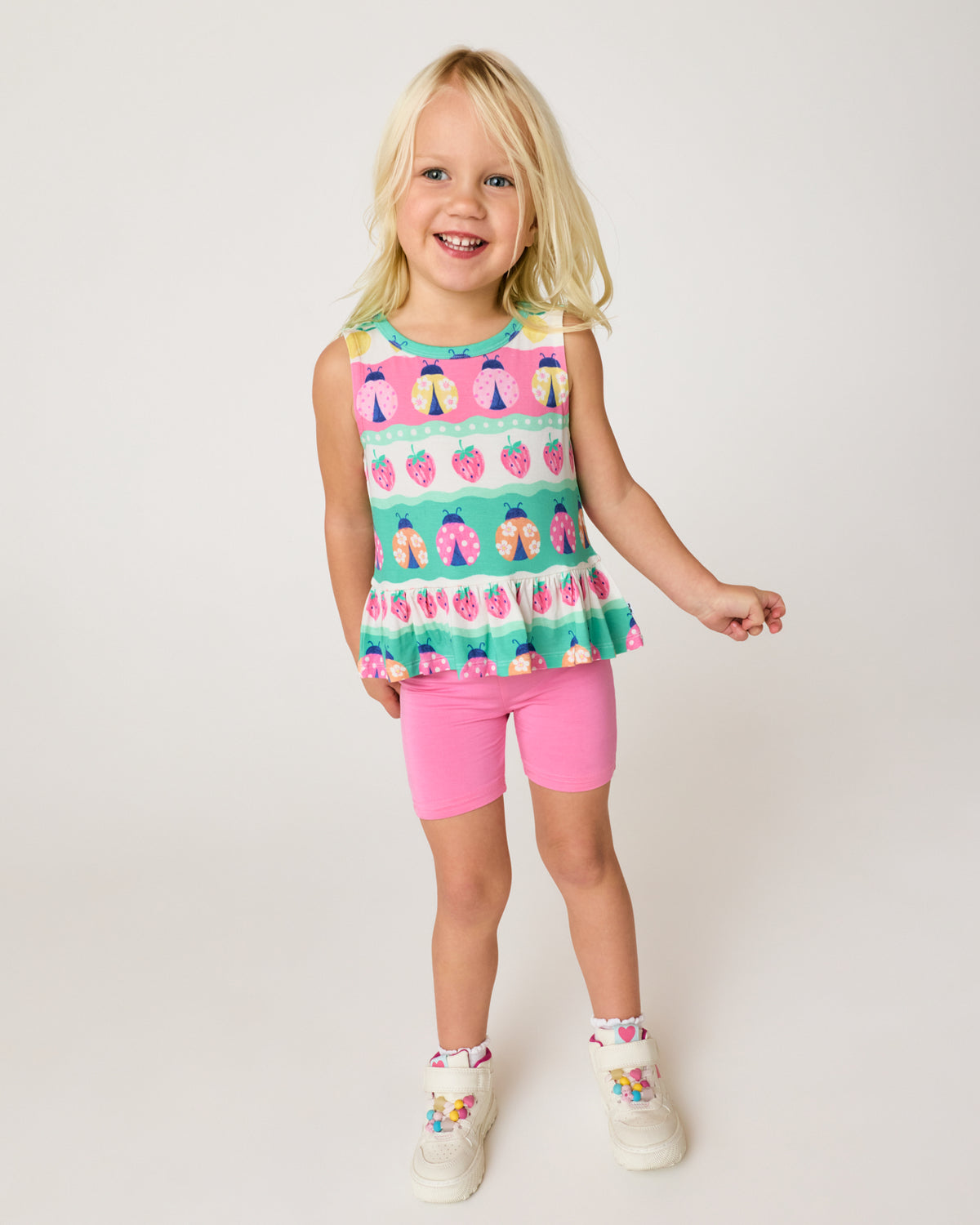 Girl wearing the Sweet Pink Bike Shorts and Ladybug Lane Peplum Tank