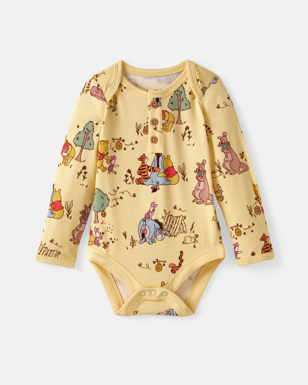 A baby long-sleeve bodysuit in pale yellow with an all-over Winnie the Pooh and friends print, featuring a three-button henley neckline and snap closures at the crotch, shown flat on a light gray background.