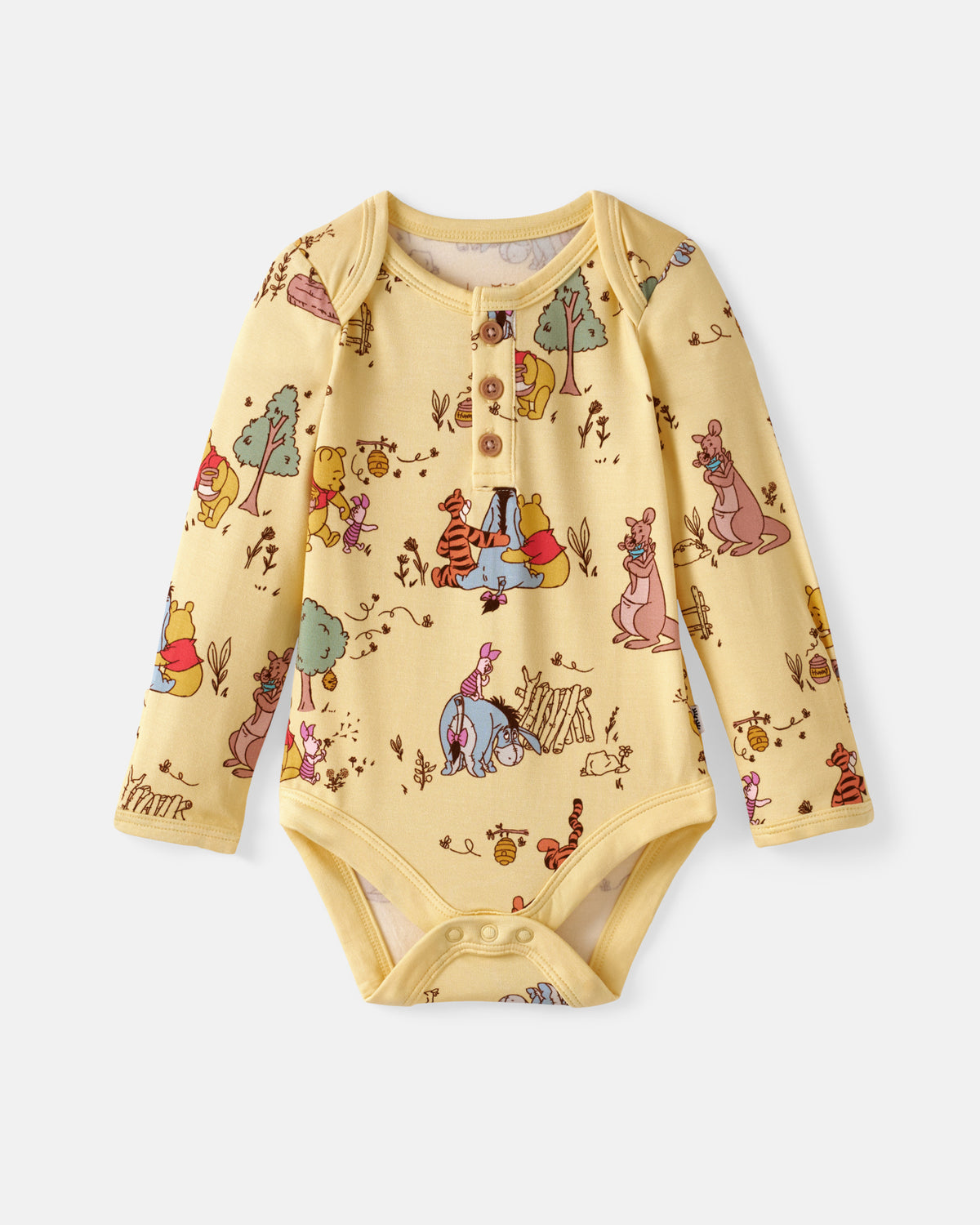 A baby long-sleeve bodysuit in pale yellow with an all-over Winnie the Pooh and friends print, featuring a three-button henley neckline and snap closures at the crotch, shown flat on a light gray background.