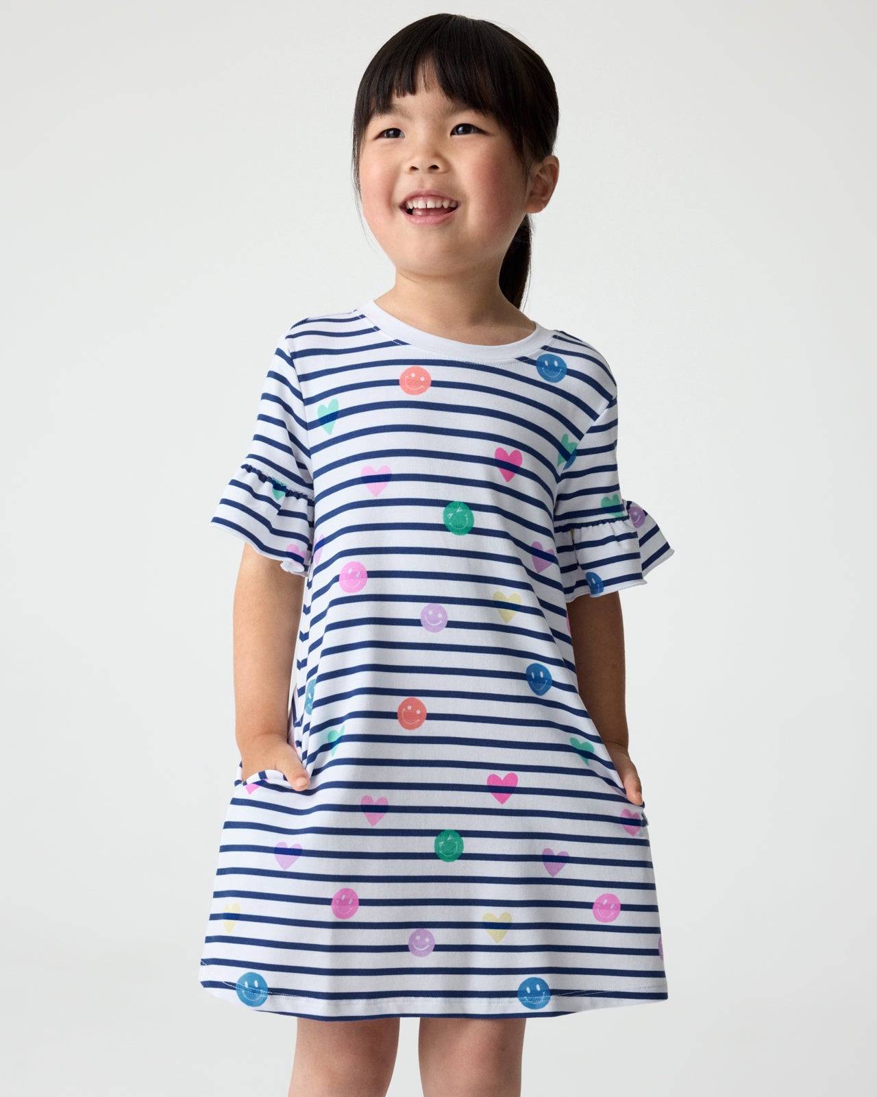 Girl wearing the Smiley Stripes Ruffled Shift Dress with her hands in the pockets
