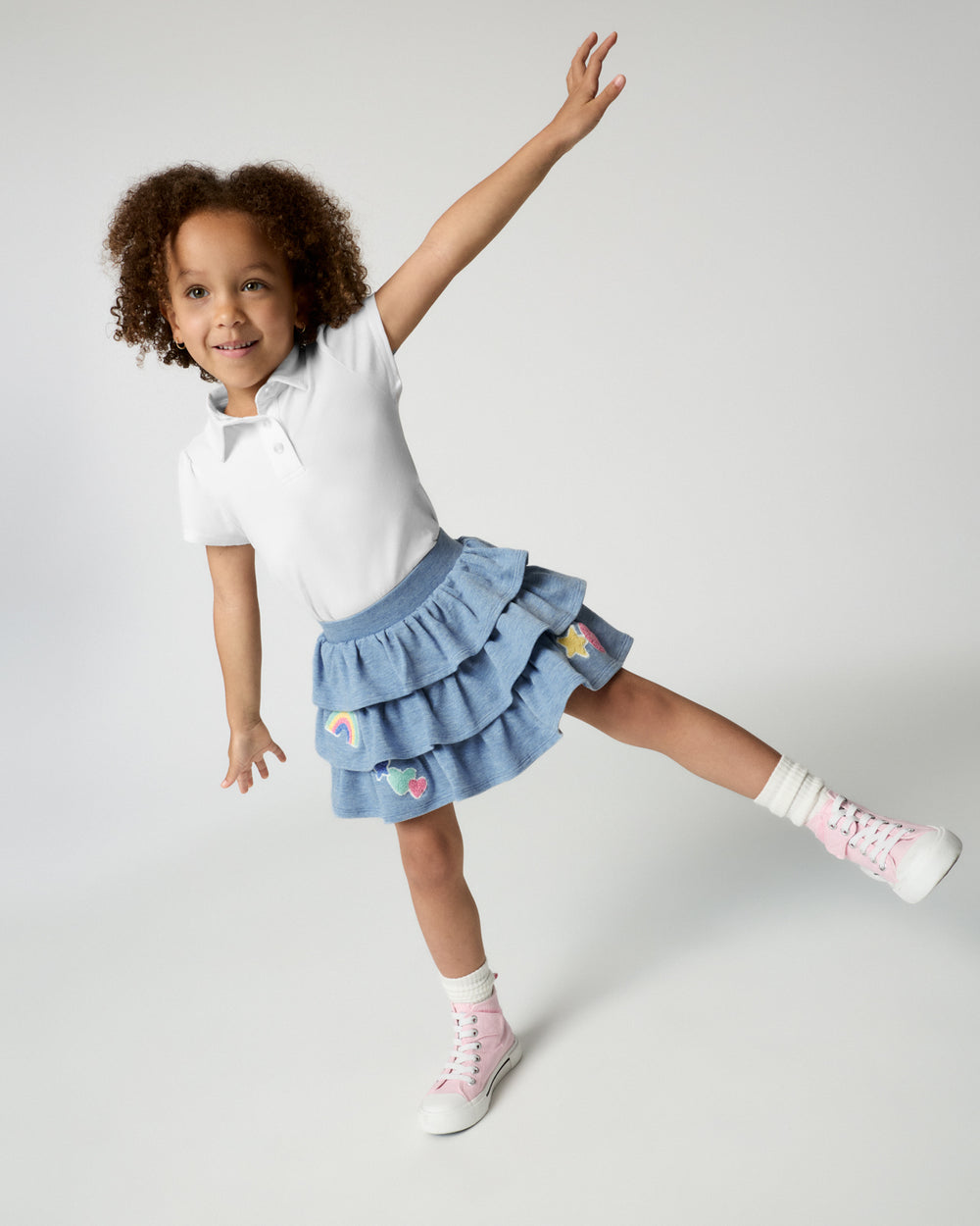Posing girl wearing the Smiley Face Tiered Skort with a white polo top