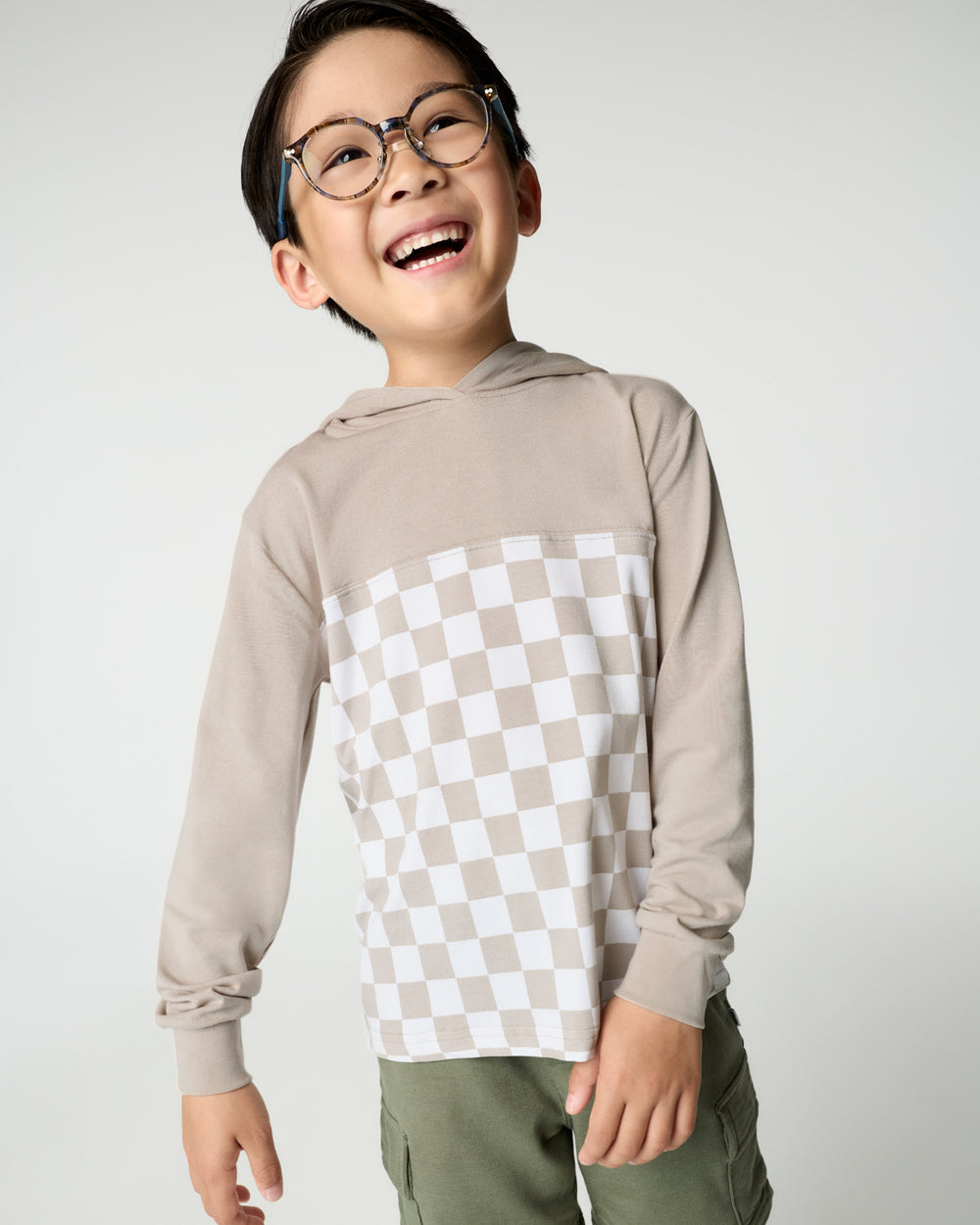 Boy wearing the Stone Checks Relaxed Hooded Tee with green bottoms