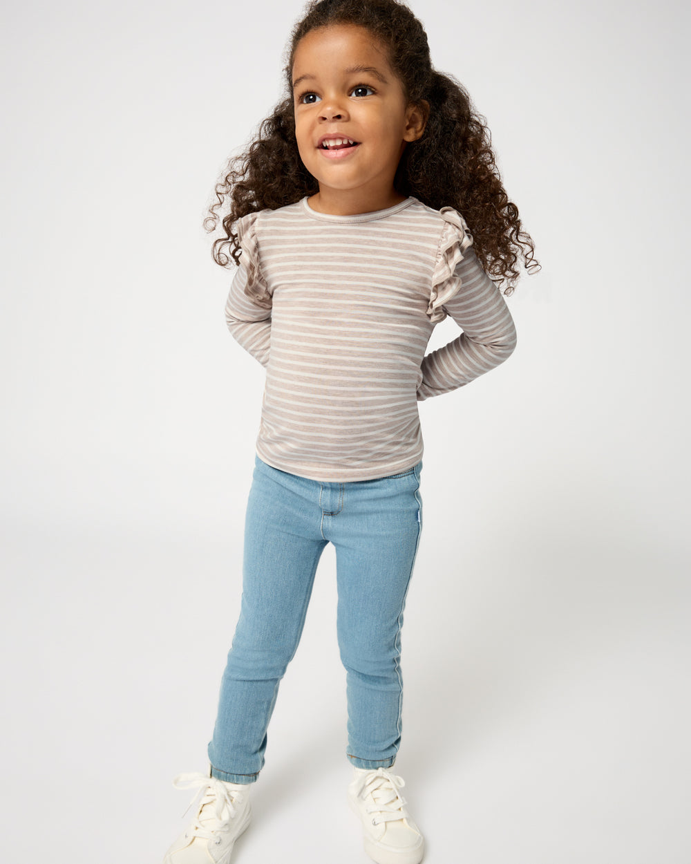 Girl wearing the Linen Heather Stripe Flutter Tee with denim jeggings