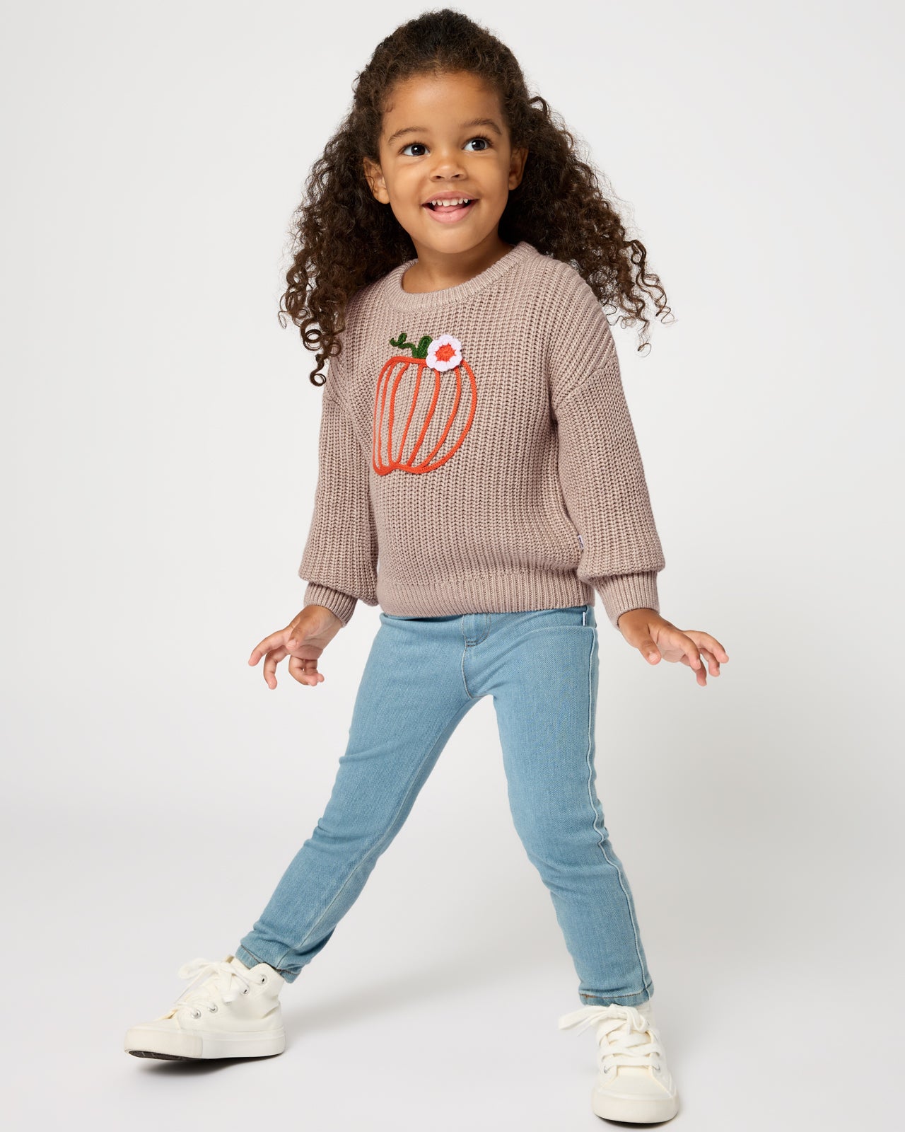 Girl wearing the Pumpkin Drop Shoulder Sweater with denim pants