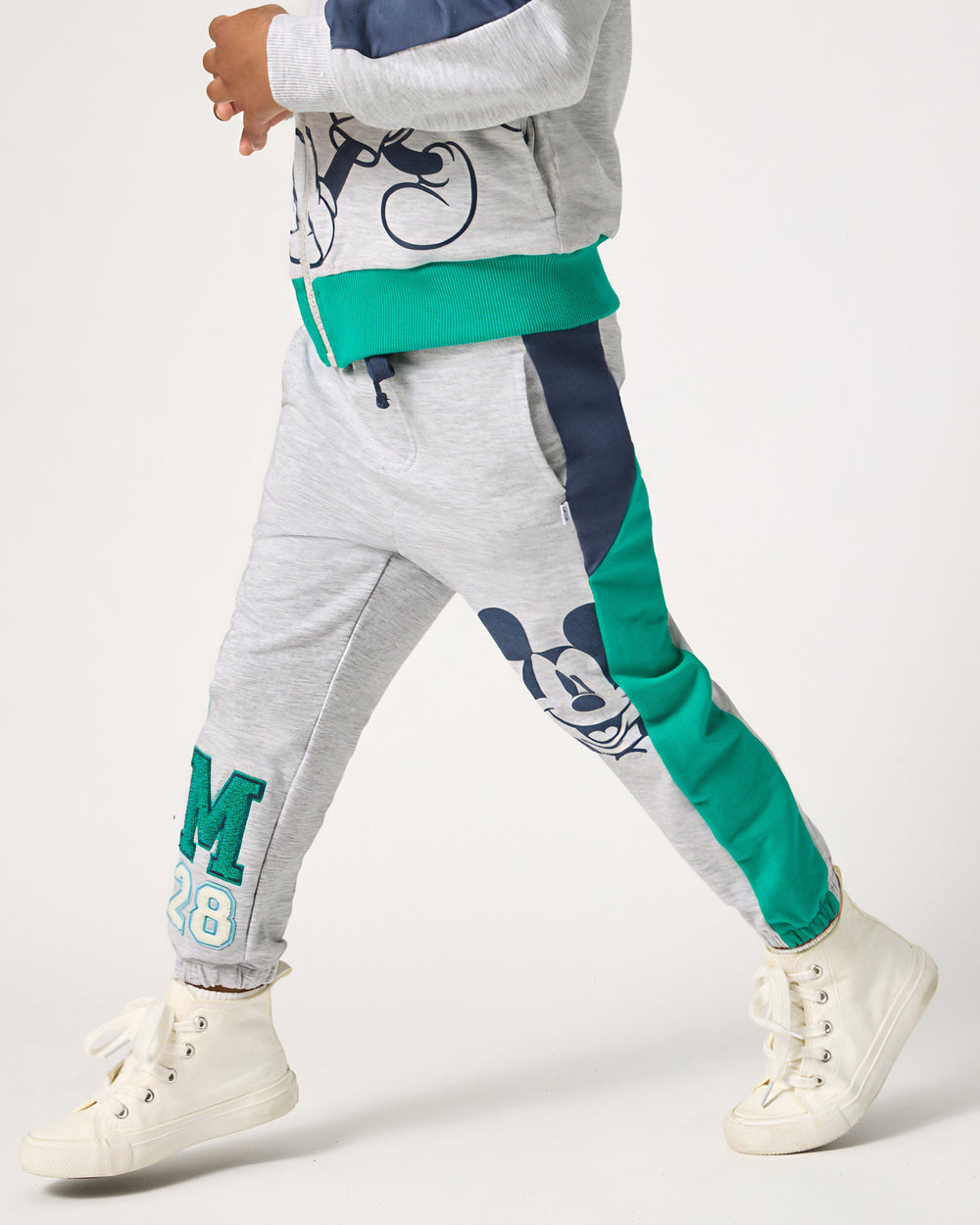 Boy wearing the Disney Mickey Mouse Sports Club Panel Jogger with white sneakers