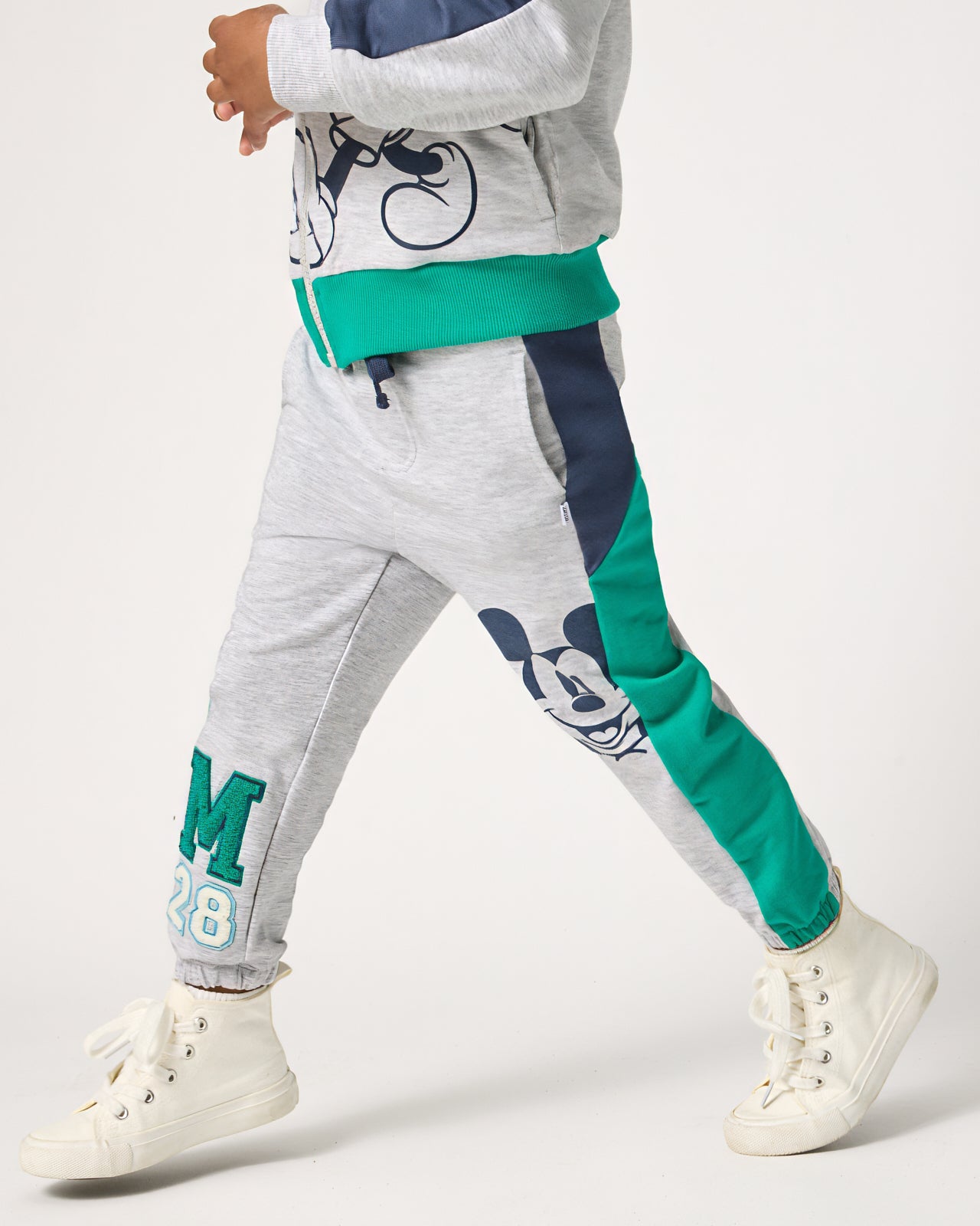 Boy wearing the Disney Mickey Mouse Sports Club Panel Jogger with white sneakers