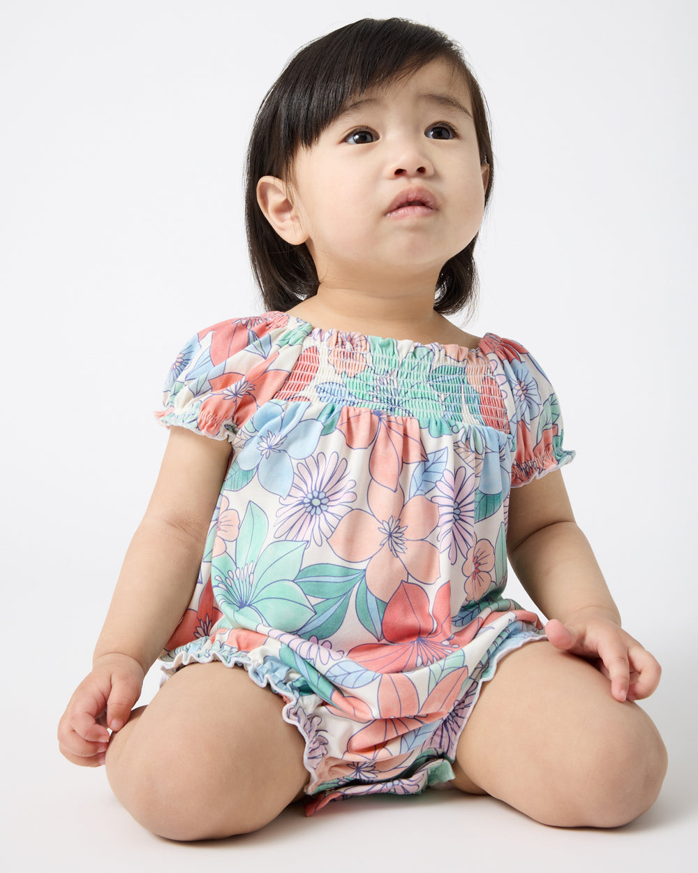 Sitting baby wearing the Shoreline Blooms Smocked Bubble Romper