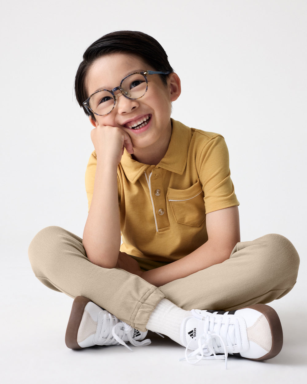 Sitting child wearing the Honey Polo Shirt with khaki joggers