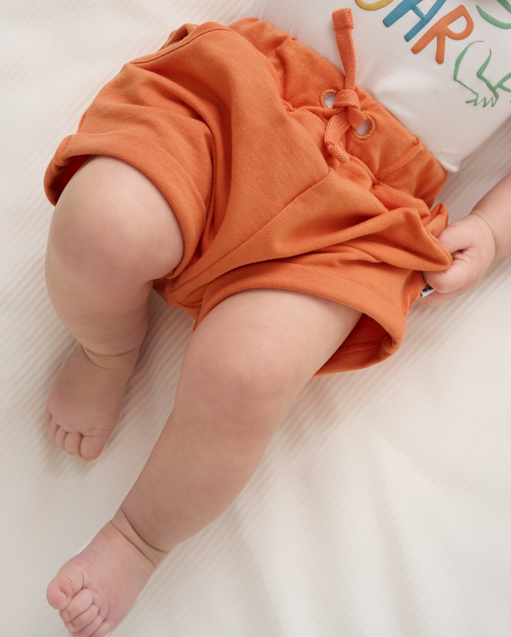 Close up of baby wearing the Orange Haze Cuffed Baby Shorts