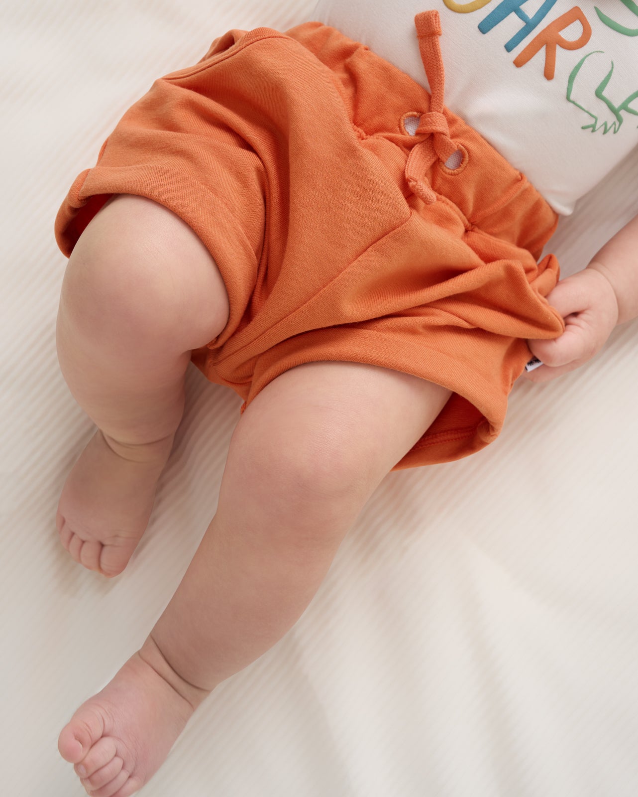 Close up of baby wearing the Orange Haze Cuffed Baby Shorts