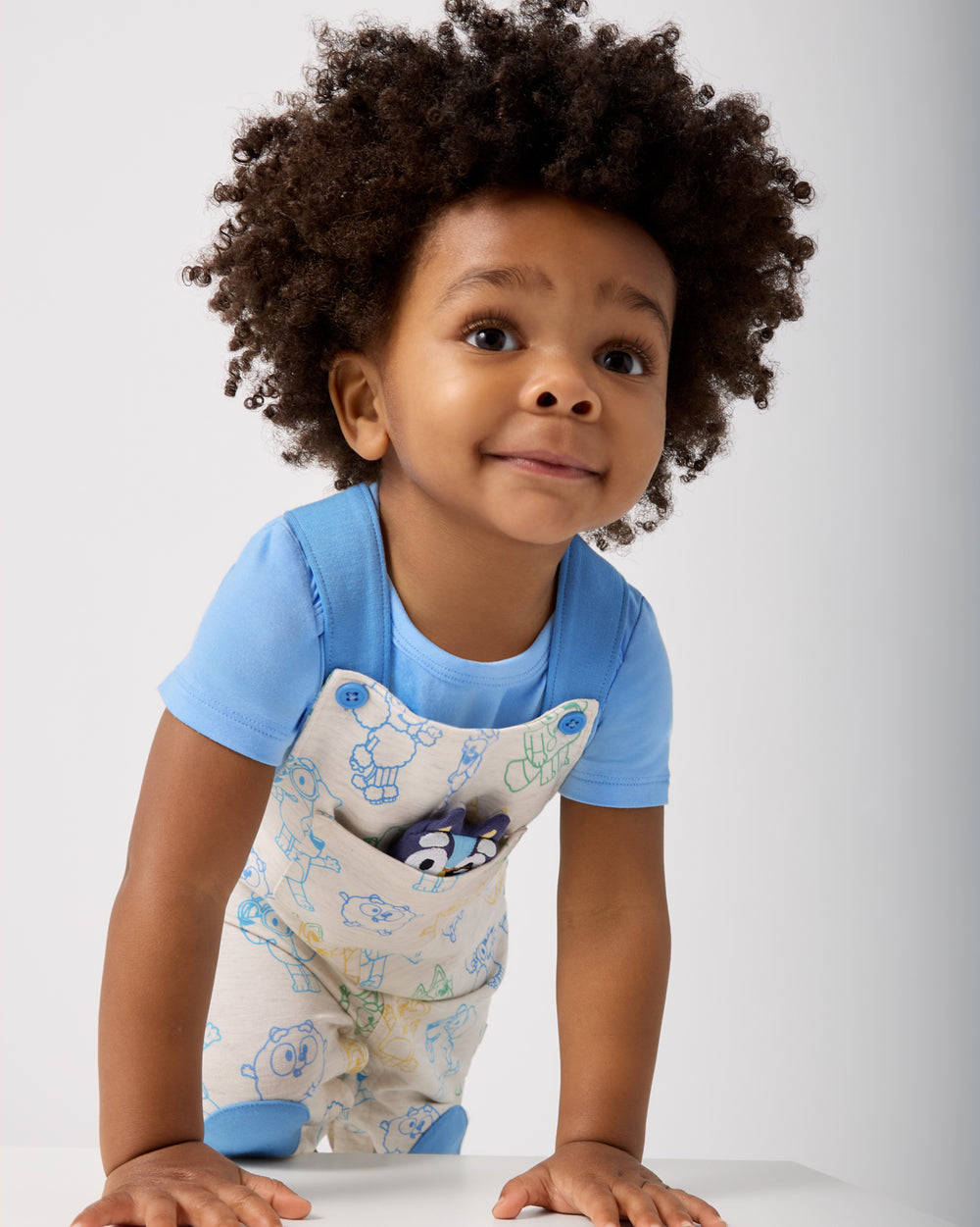 Boy wearing the Bluey Playtime Crew Overall layered over a blue onesie