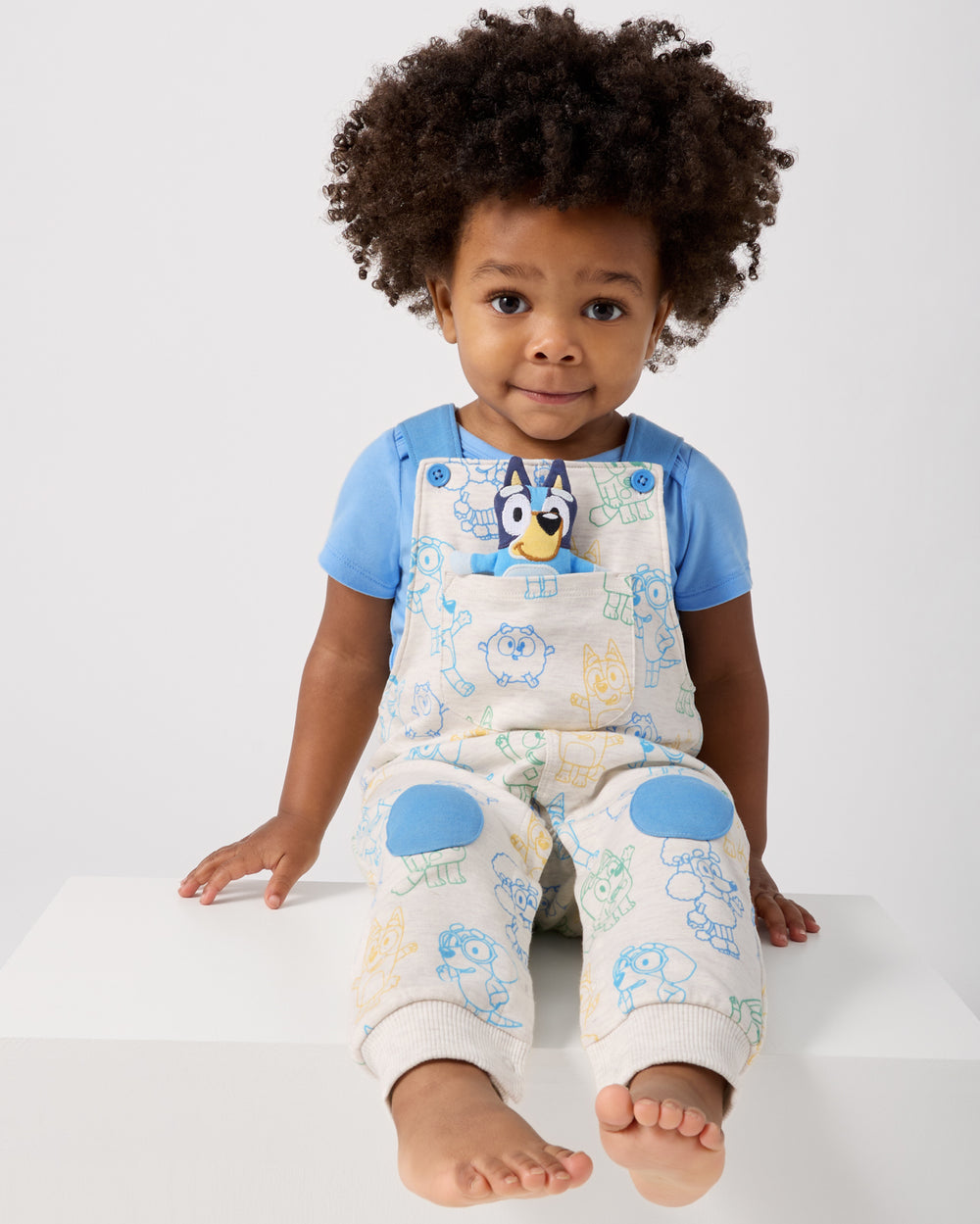 Sitting boy wearing the Bluey Playtime Crew Overall