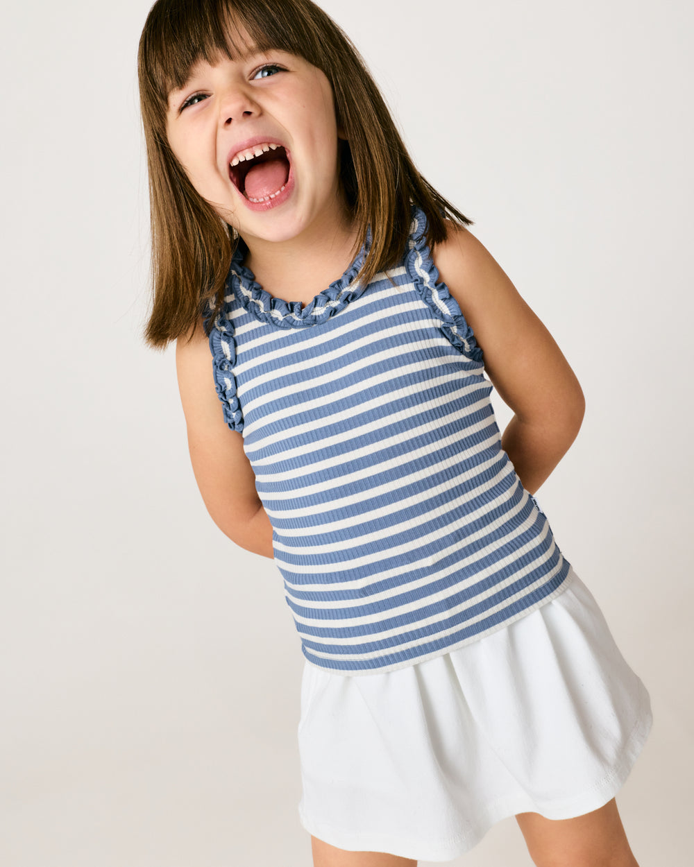 Girl wearing the Infinite Blue Stripe Ribbed Ruffle Tank with a white skirt