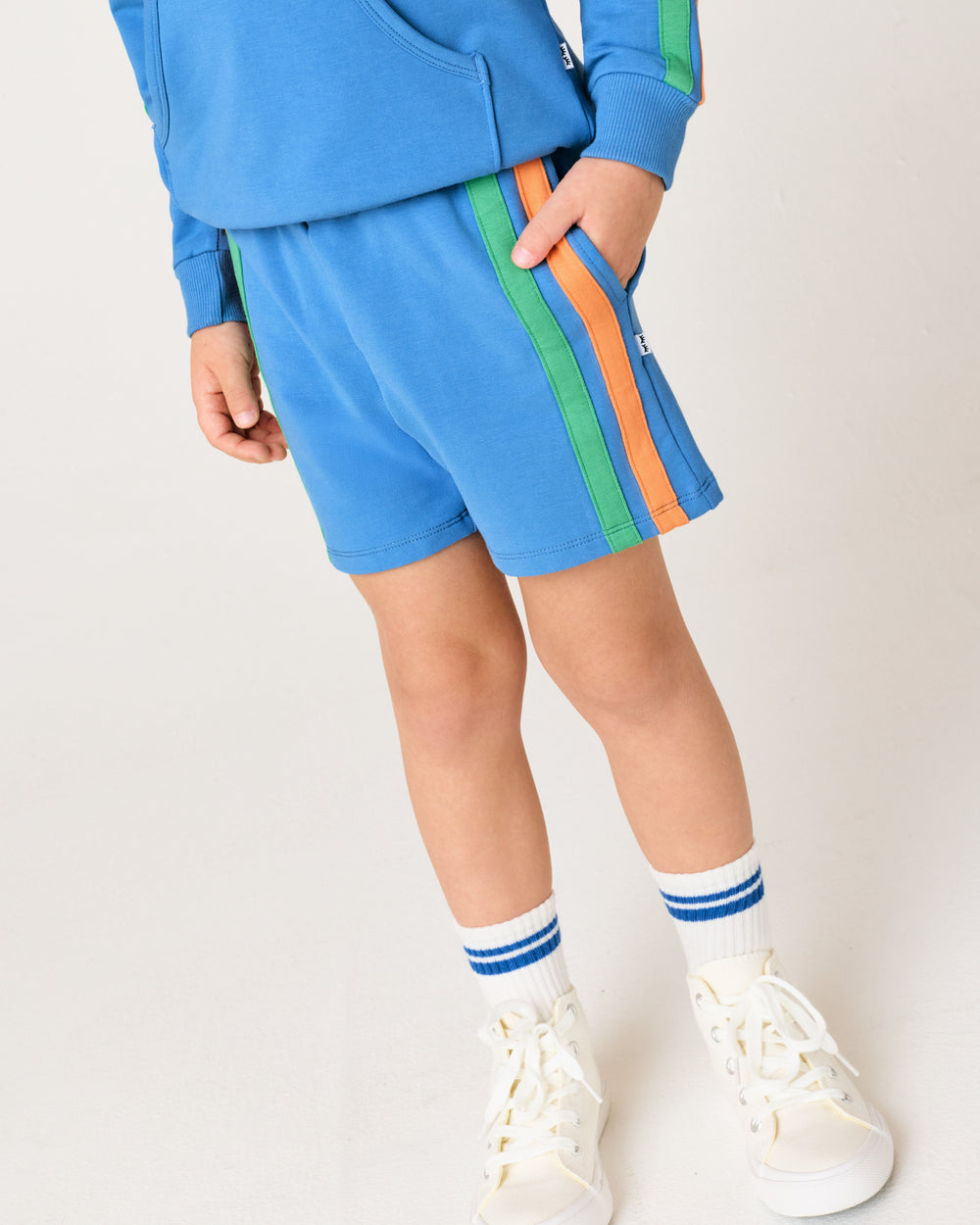 Close up of boy wearing the Major Blue Side Stripe Short with his hand in the pocket