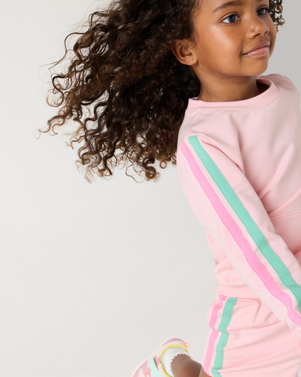 Close up of running child wearing the Pink Blossom Pocket Crewneck