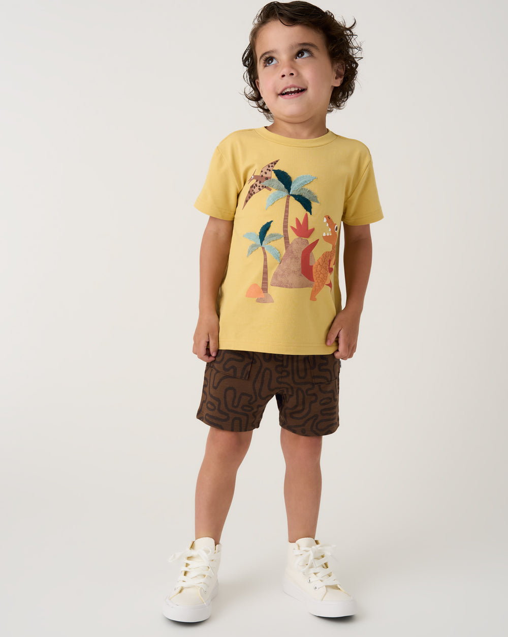 Boy wearing the Dino Maze Shorts with a yellow tee