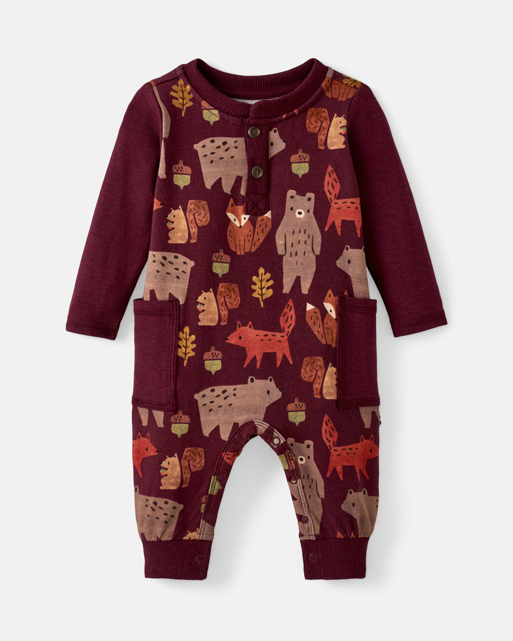 A baby long-sleeve romper in deep burgundy with an all-over woodland forest print of bears, foxes, acorns, and leaves, featuring a buttoned henley neckline and front pockets.