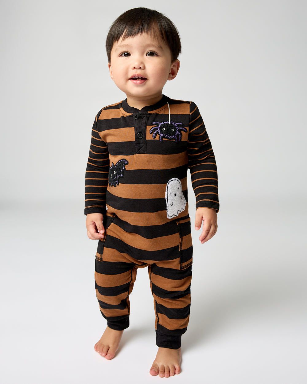 Standing toddler wearing the Spooky Stripes Henley Romper