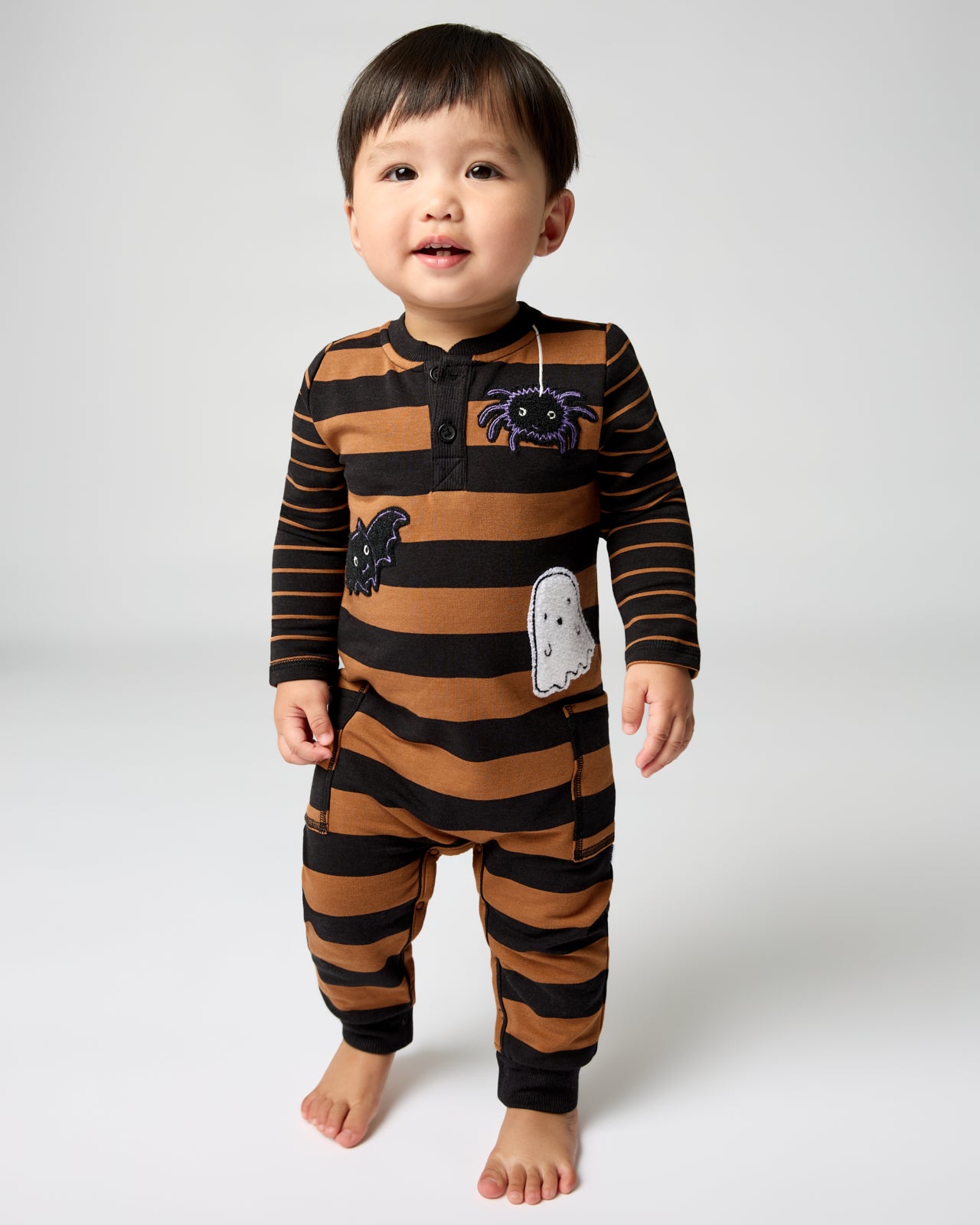 Standing toddler wearing the Spooky Stripes Henley Romper