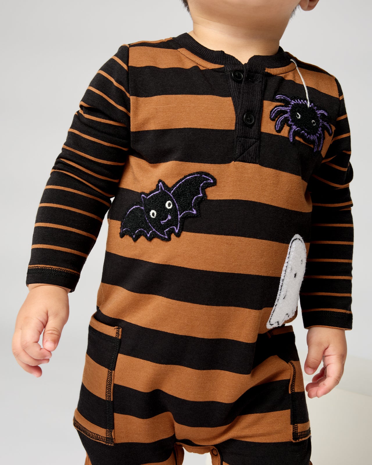 Close up of toddler wearing the Spooky Stripes Henley Romper