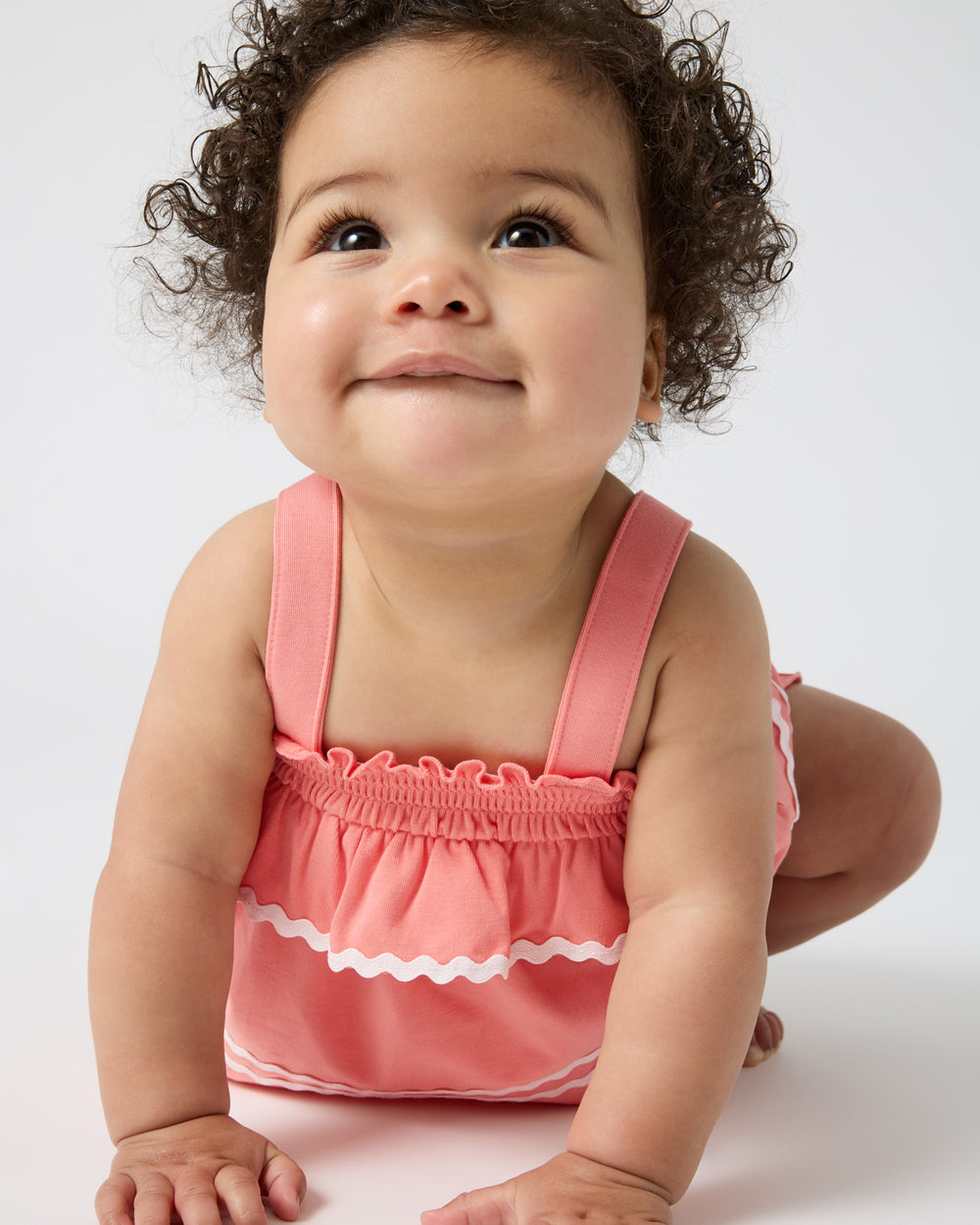 Crawling baby wearing the Beach Coral Smocked Top with Bloomer