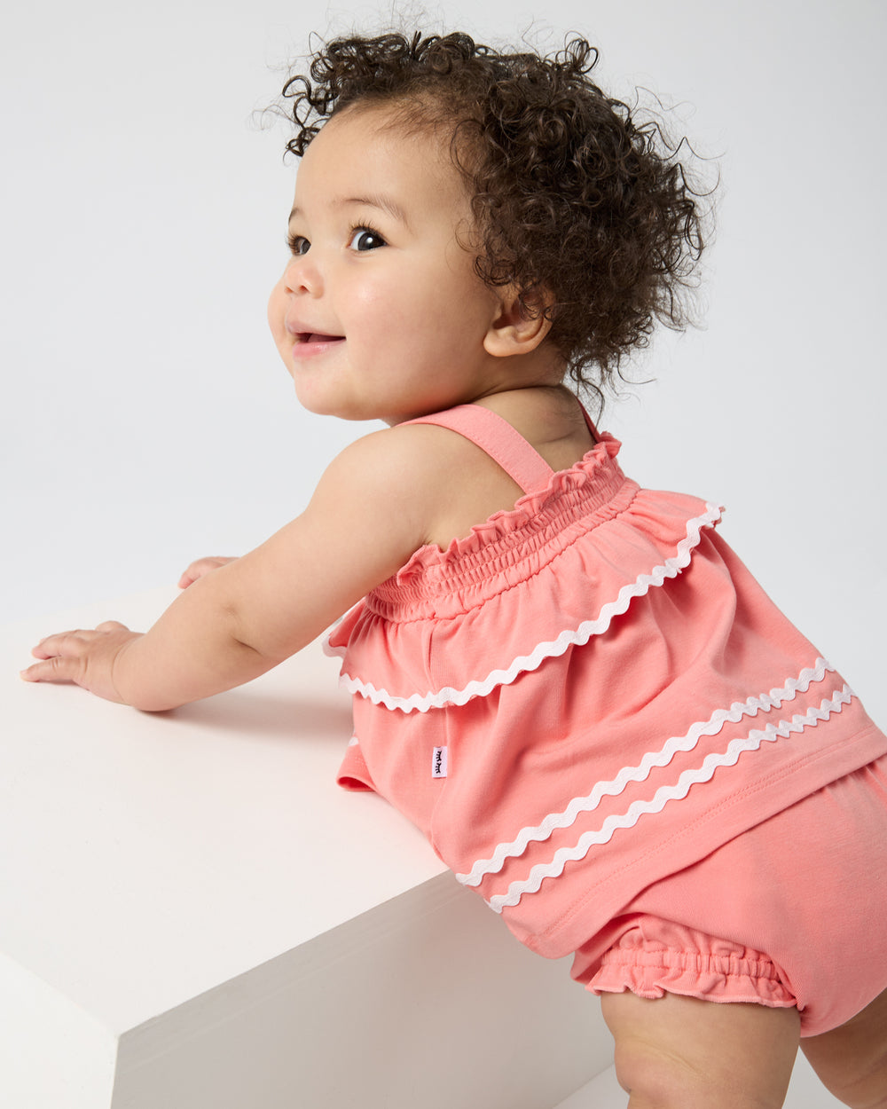 Standing baby wearing the Beach Coral Smocked Top with Bloomer