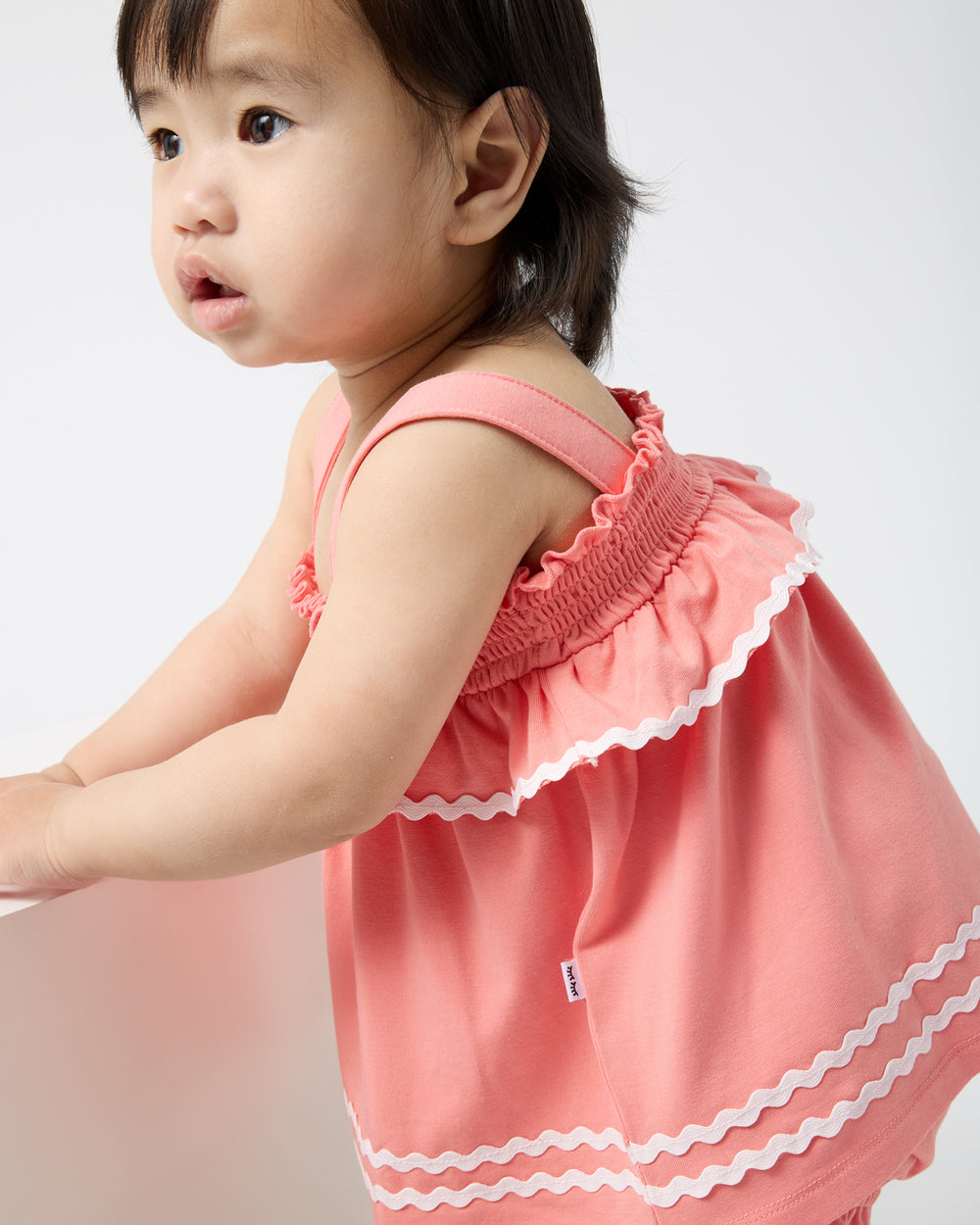 Close up of baby wearing the Beach Coral Smocked Top with Bloomer