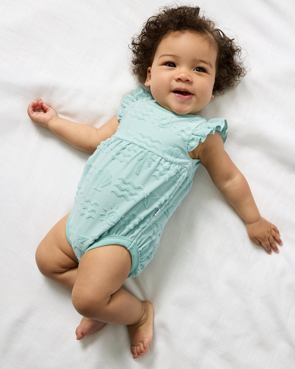 Overhead view of newborn wearing the Coastal Rays Flutter Bodysuit