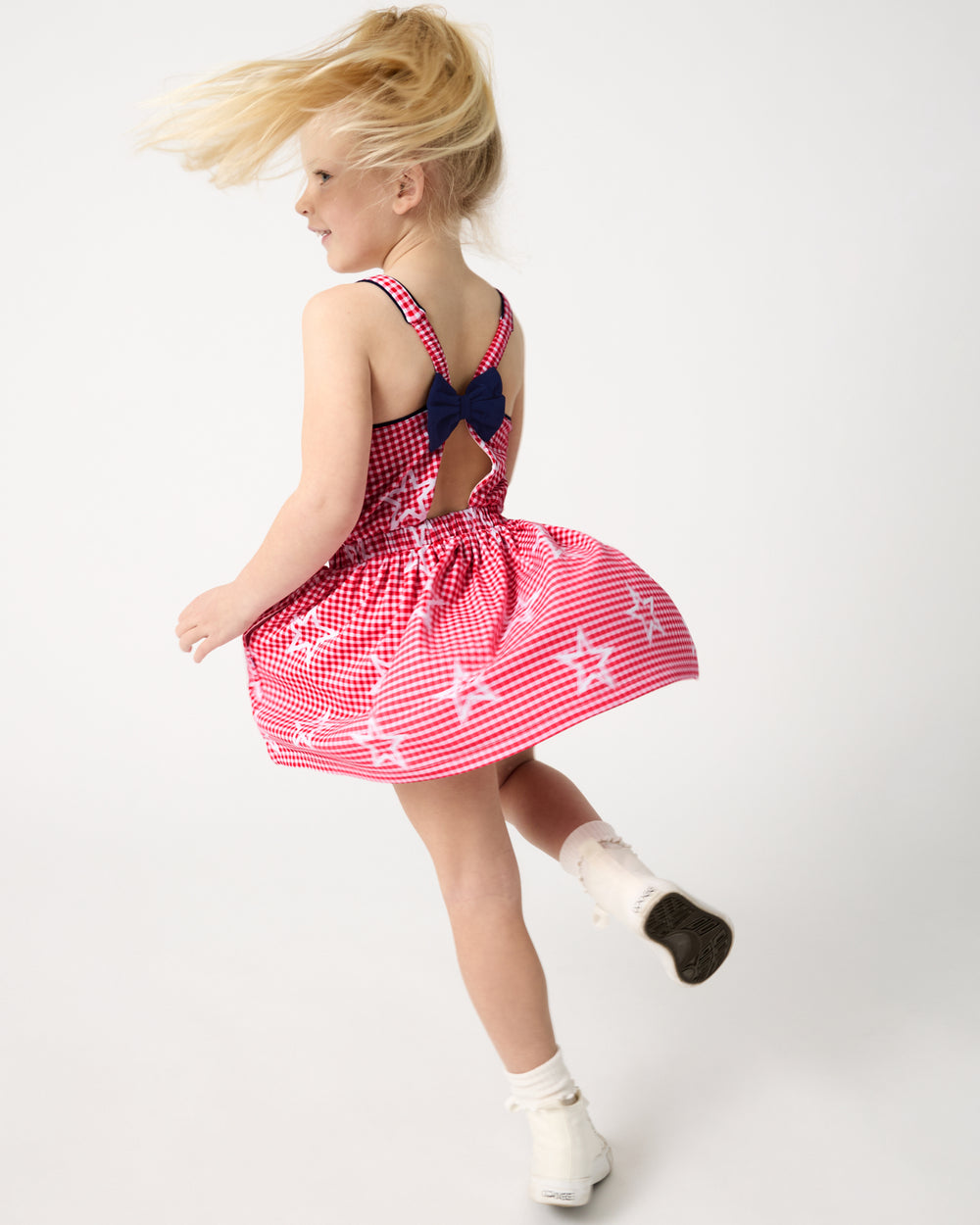 Child in motion wearing the Celebration Gingham Bow Back Twirl Dress