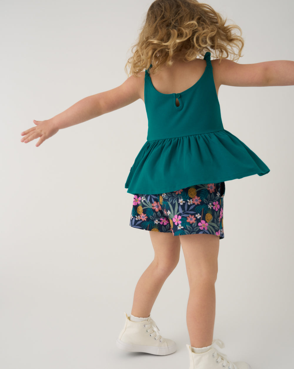 Child in motion wearing the Tropical Garden Smocked Shorts with a green tank