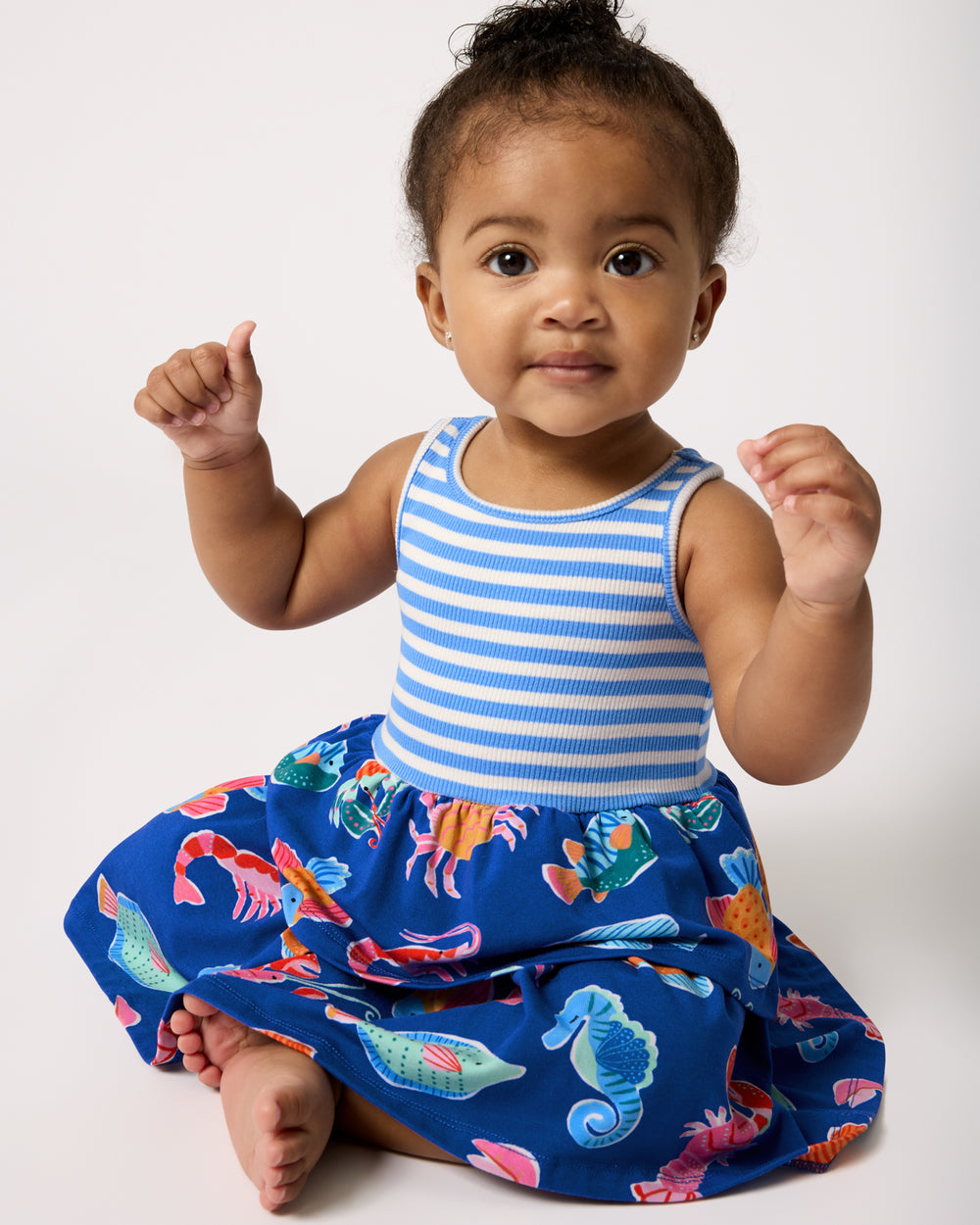 Sitting baby wearing the Tidepool Party Tiered Dress with Bloomer