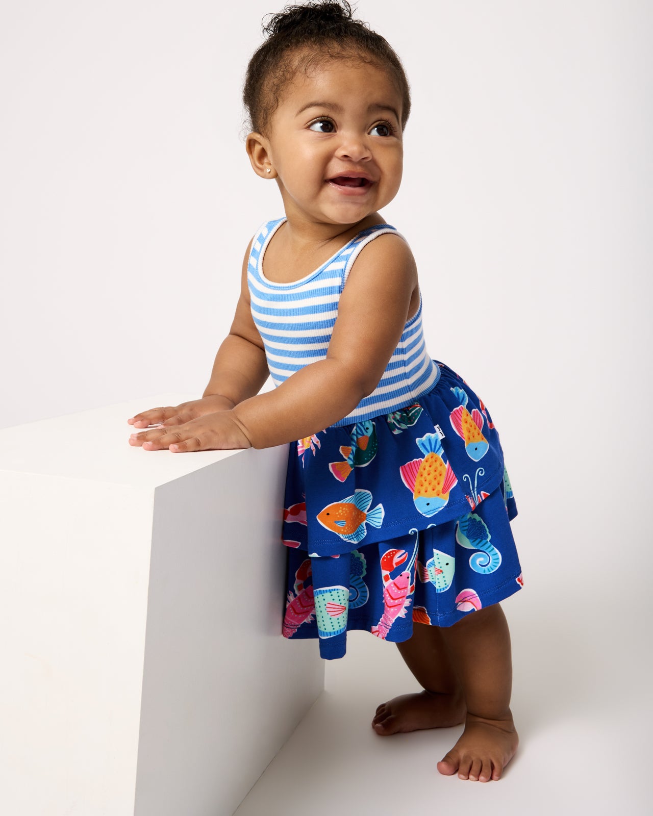 Standing baby wearing the Tidepool Party Tiered Dress with Bloomer