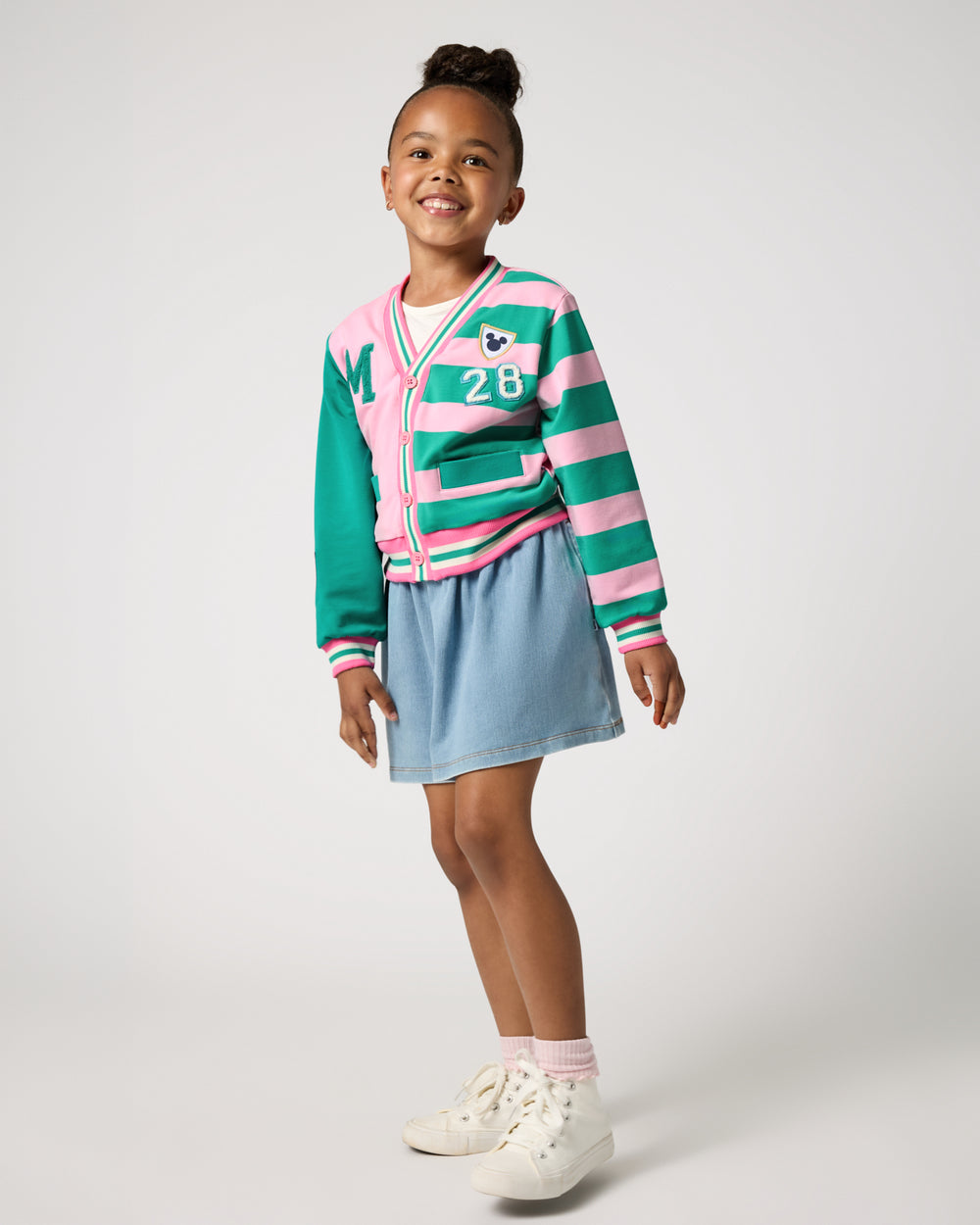 Girl wearing the Disney Mickey Mouse Sports Club Varsity Cardigan and denim skort